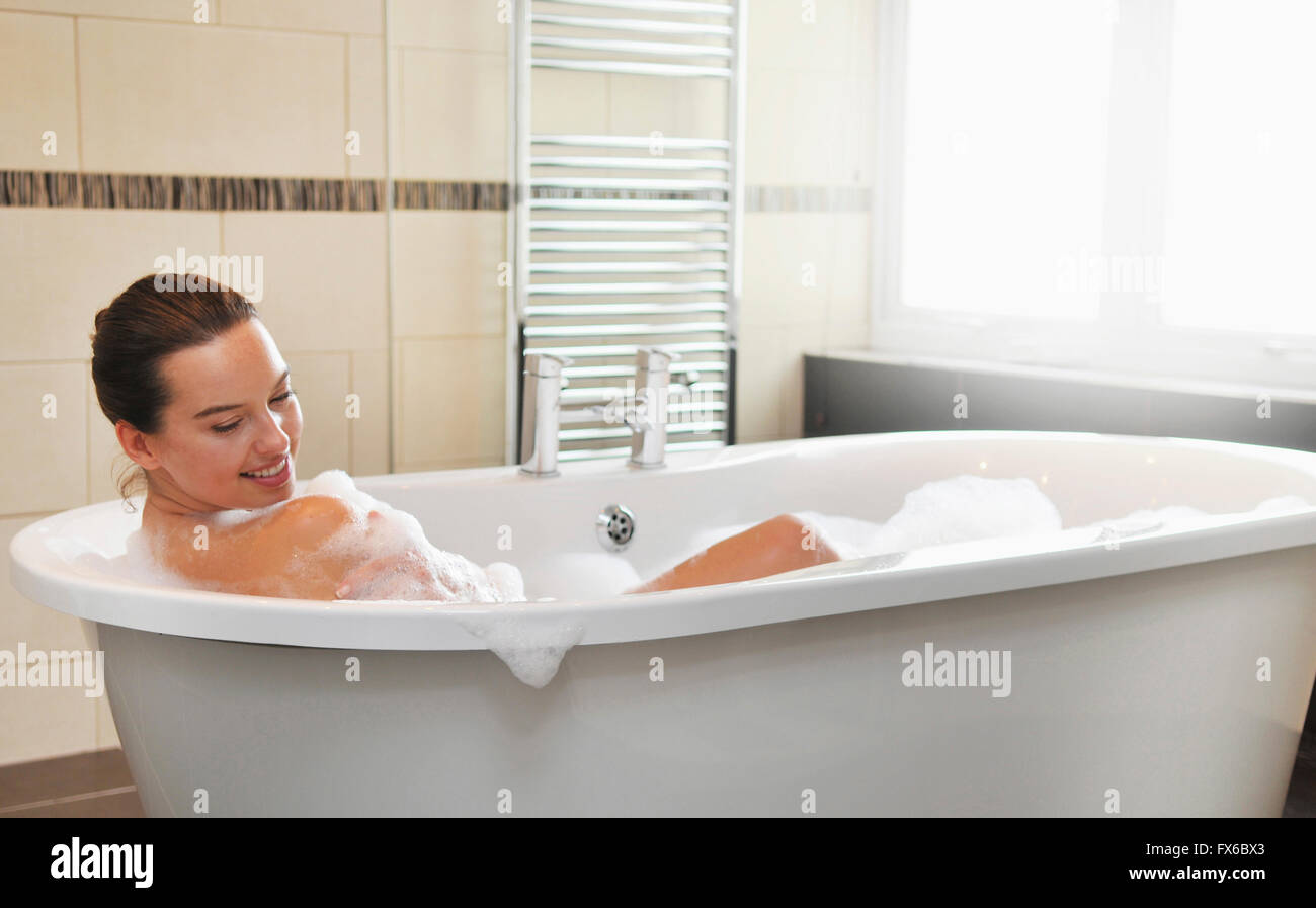 Caucasian woman taking bubble bath in bathroom Stock Photo