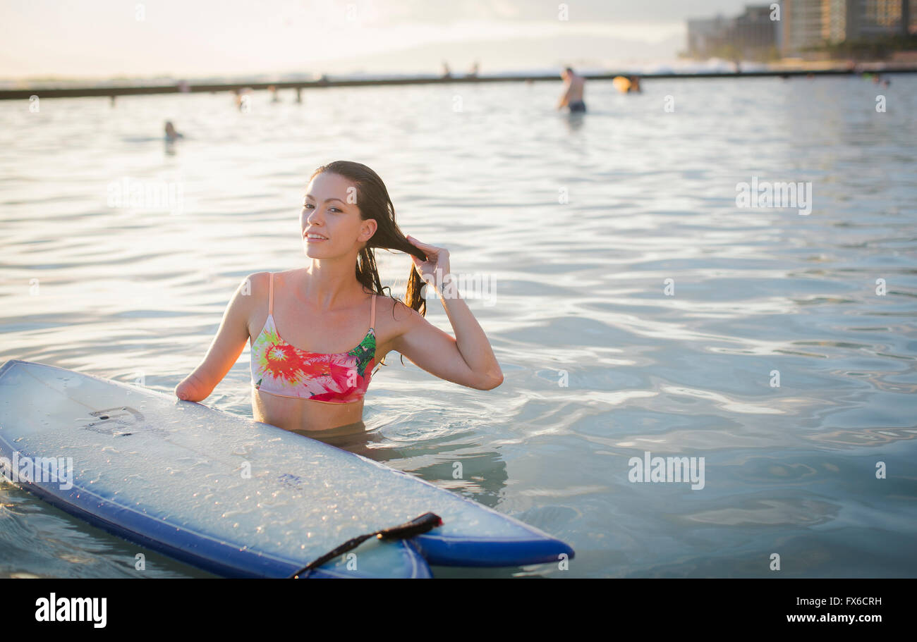 Mixed race amputee with surfboard in ocean Stock Photo