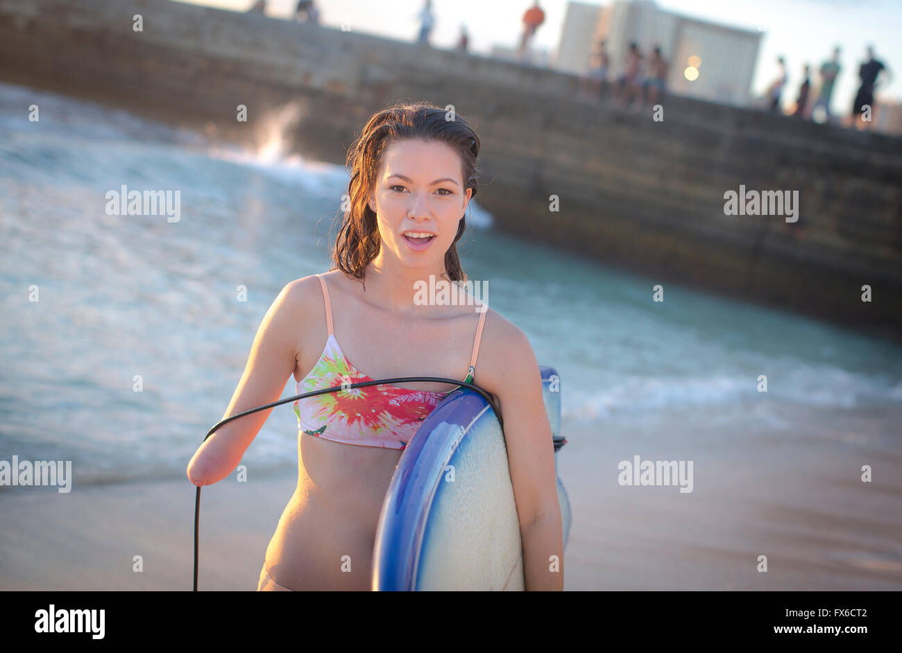 Mixed race amputee carrying surfboard on beach Stock Photo