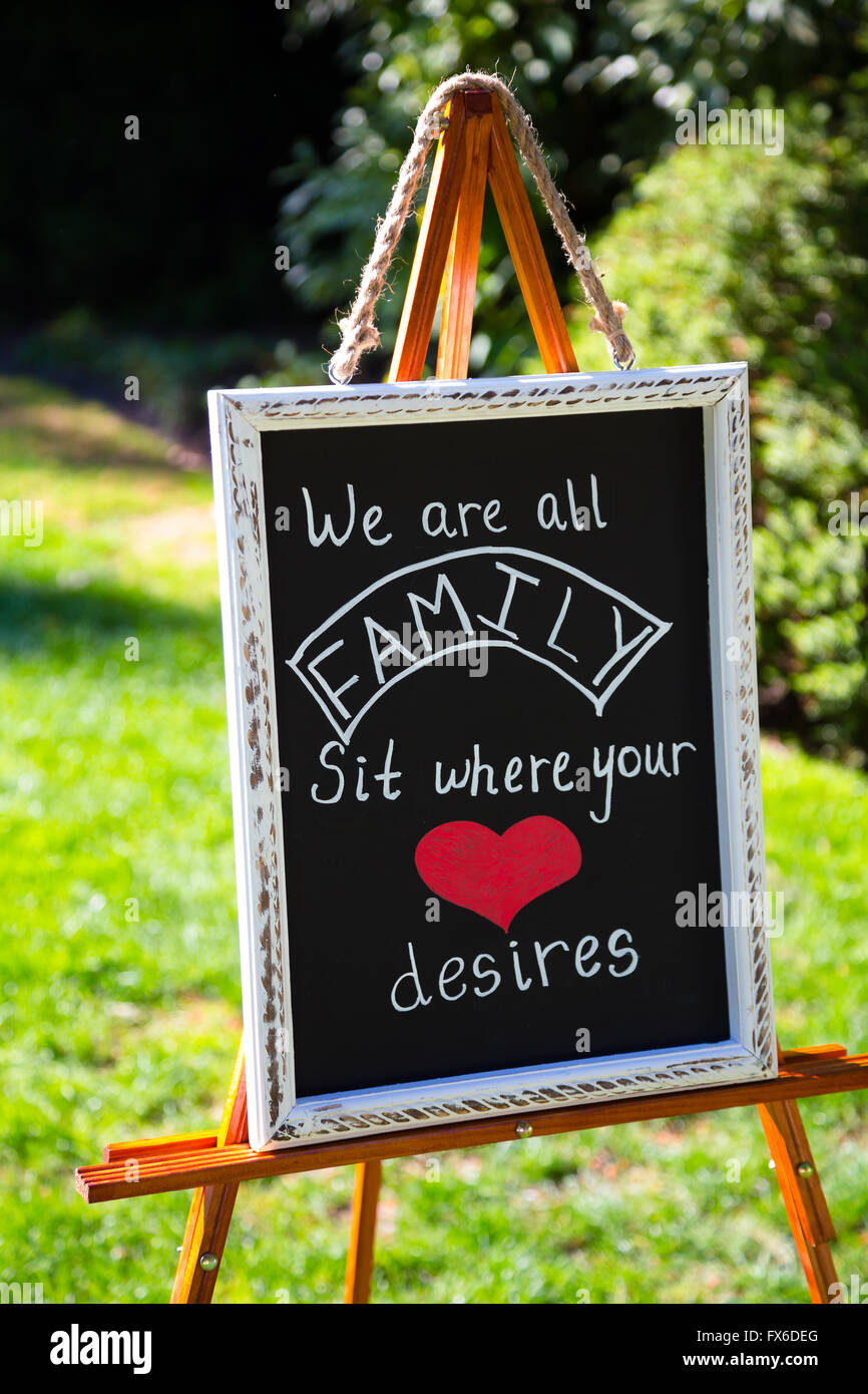 Wedding sign for seating arrangements says we are all family sit where your heart desires. Stock Photo