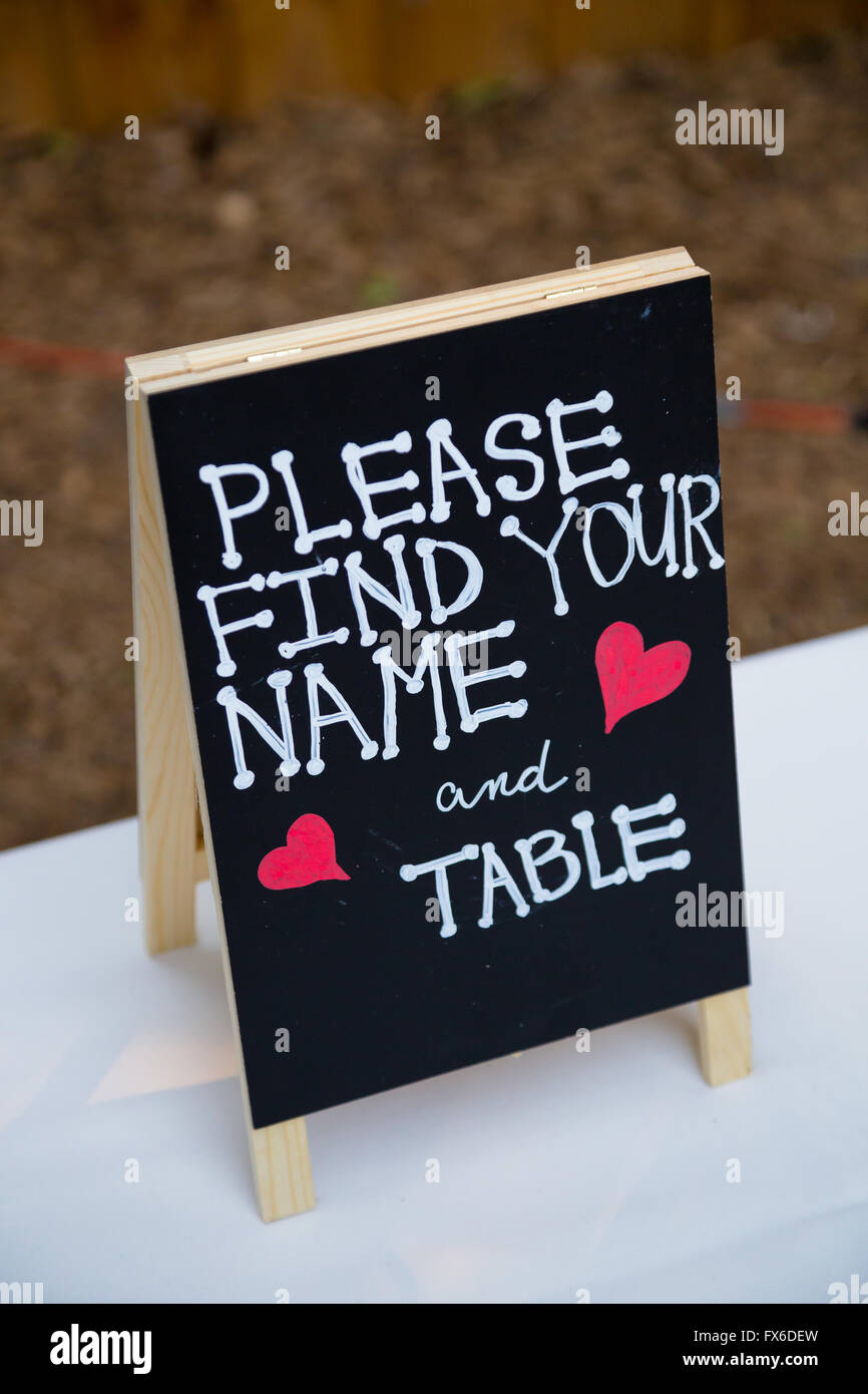 Reception tables have a seating arrangement and this sign says please find your name and table. Stock Photo