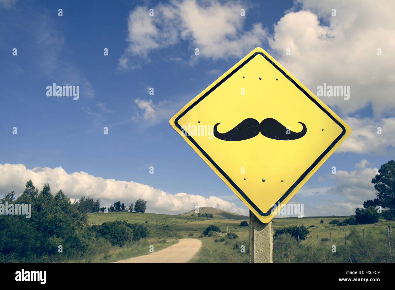 Hipster mustache funny facial hair concept icon road sign on empty countryside nature landscape, vintage filter effect. Stock Photo