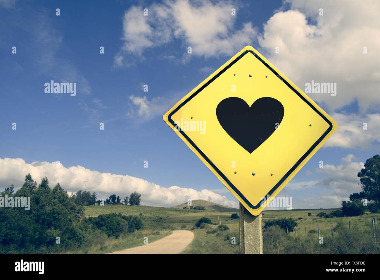 Love heart shape romantic concept icon road sign on empty countryside nature landscape, vintage filter effect. Stock Photo