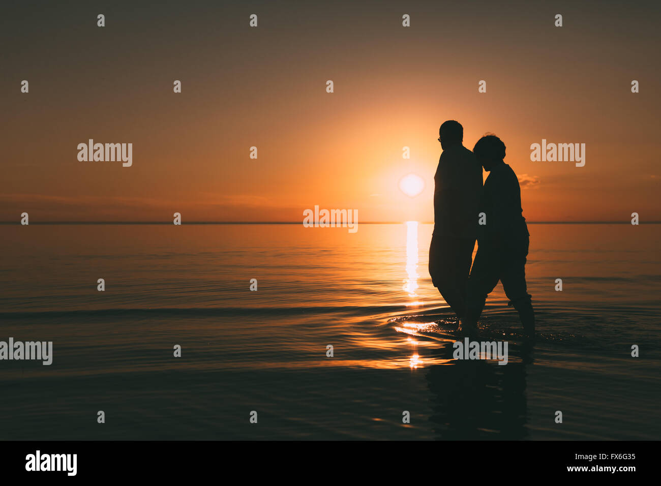 Silhouette of adult couple standing in the sea against a sunset Stock ...
