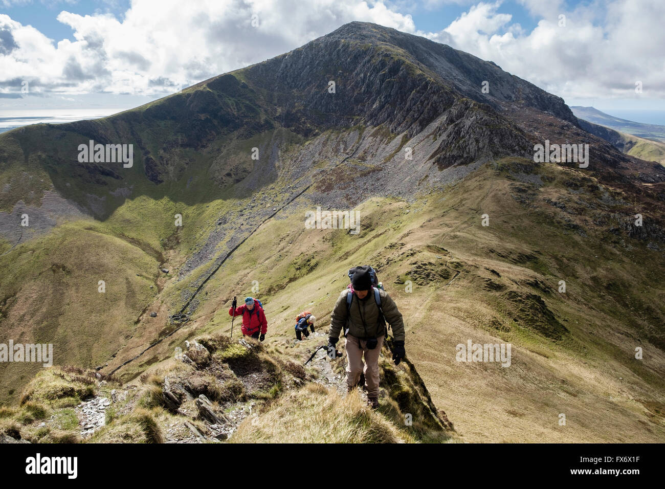 Hikers ascending path up Mynydd Tal-y-mignedd with view west to Craig Cwm Silyn on Crib Nantlle Ridge in Snowdonia National Park mountains. Wales UK Stock Photo