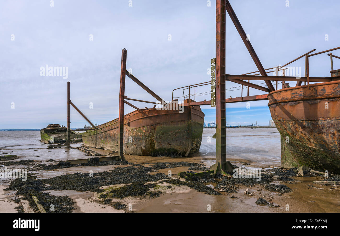 Disused ship yard with derelict iron ships and rusting rails for winching boats all flanked by mud banks of Humber estuary. Stock Photo