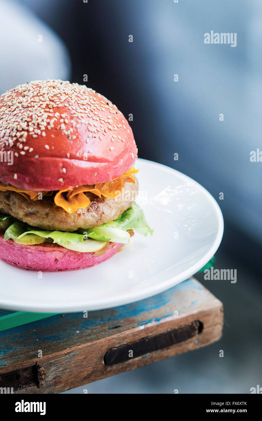 chicken burger with gherkins and crisps in beetroot bread bun Stock