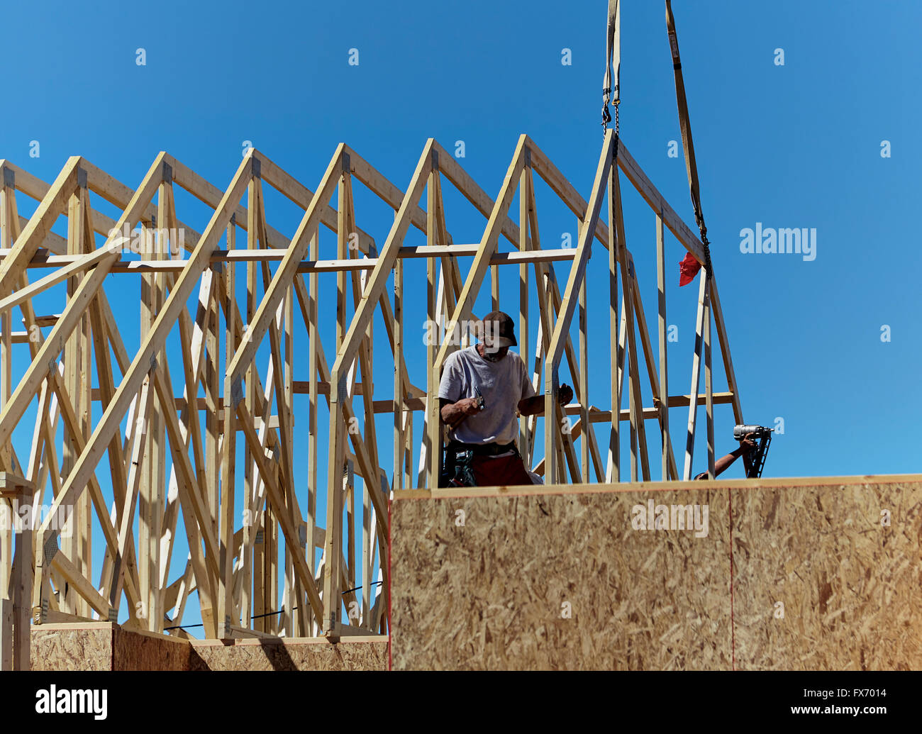 Construction workers installing roof trusses on a new home Stock Photo