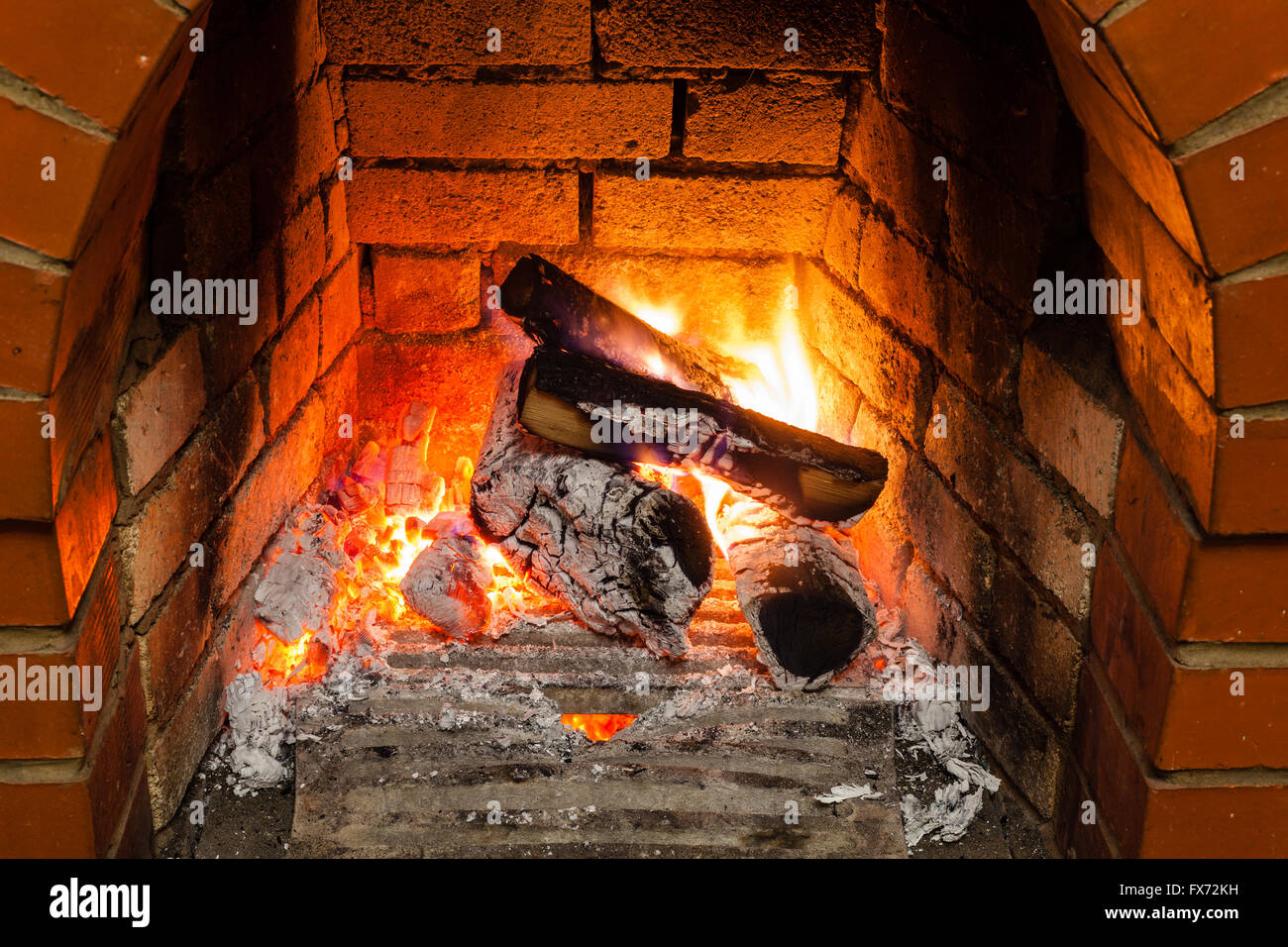 ash, coal and burning wood in fireplace in country cottage Stock Photo