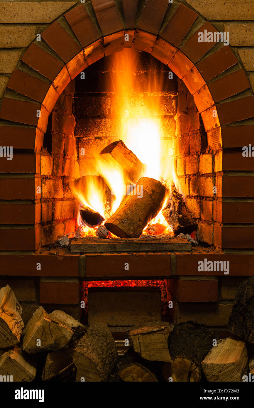 firewood and fire in fireplace in country cottage Stock Photo