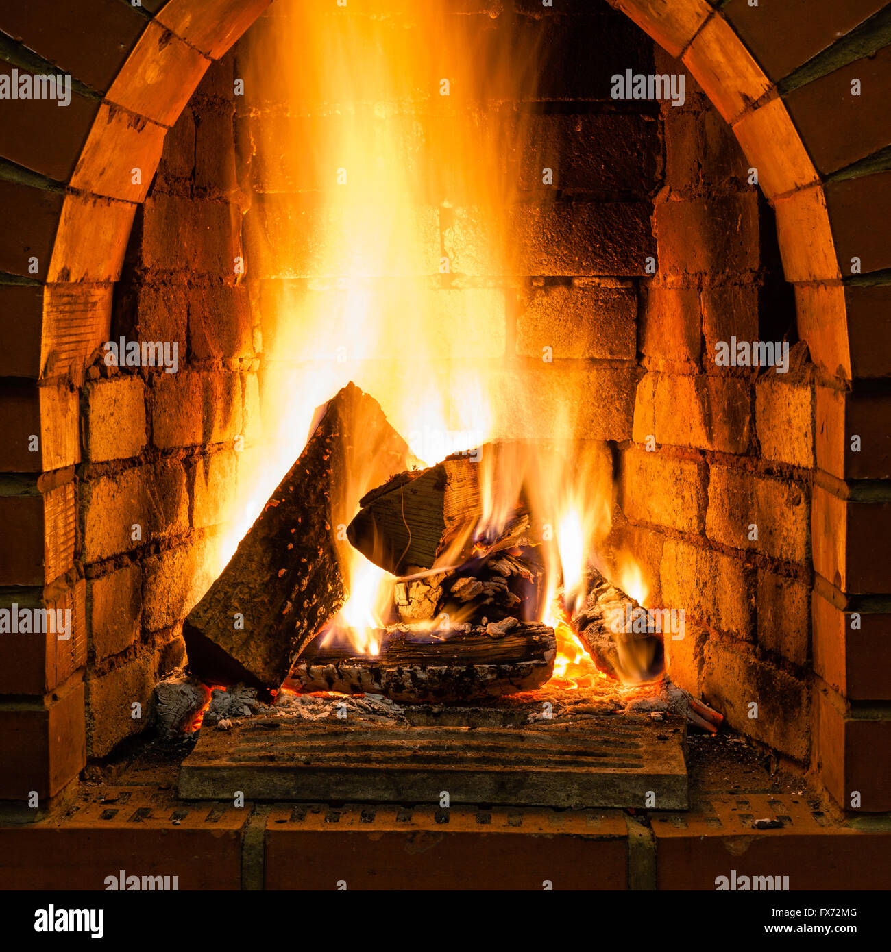 open fire in fire-box of brick fireplace in country cottage Stock Photo