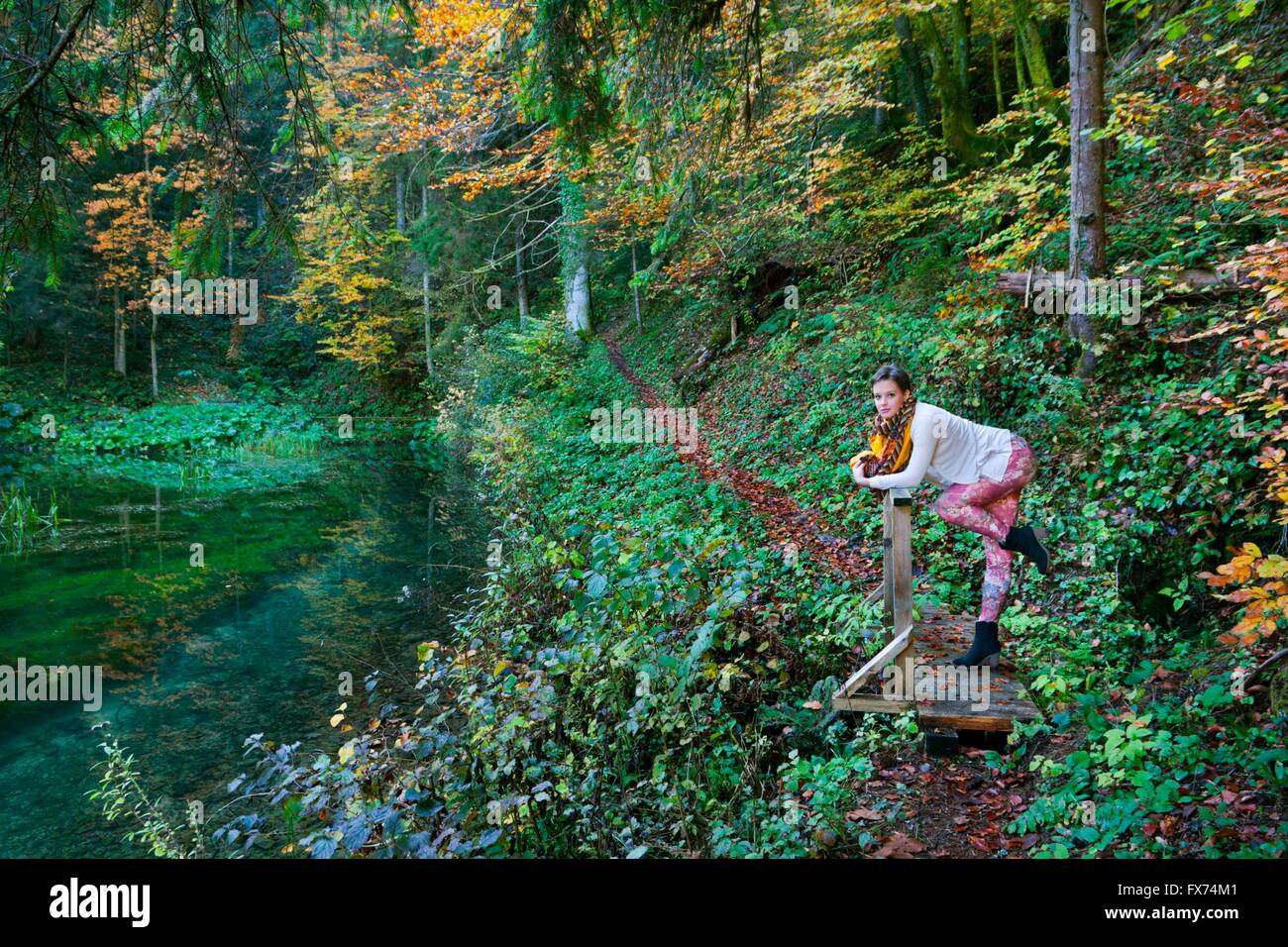 Short-haired teenager girl in woodland forest posing pose colorful pants Autumn Fall trail lake deep trees strike pose striking Stock Photo