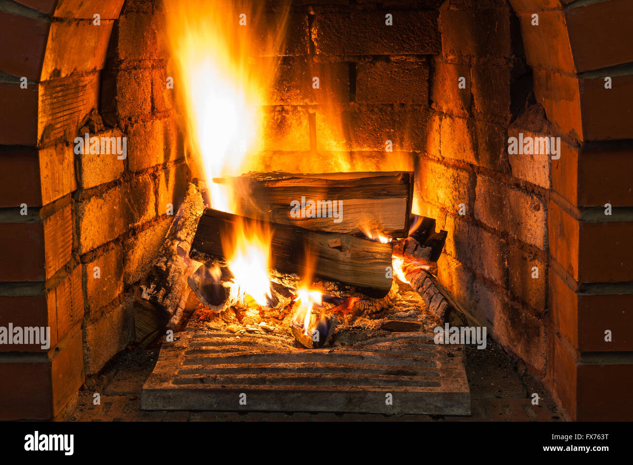 burning wood in brick fireplace in country cottage Stock Photo