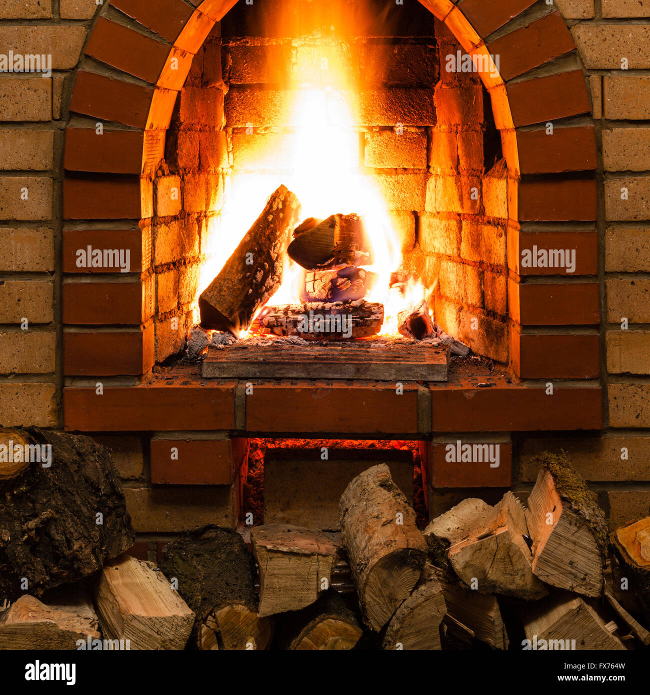 stack of wood and tongues of fire in indoor brick fireplace in country cottage Stock Photo
