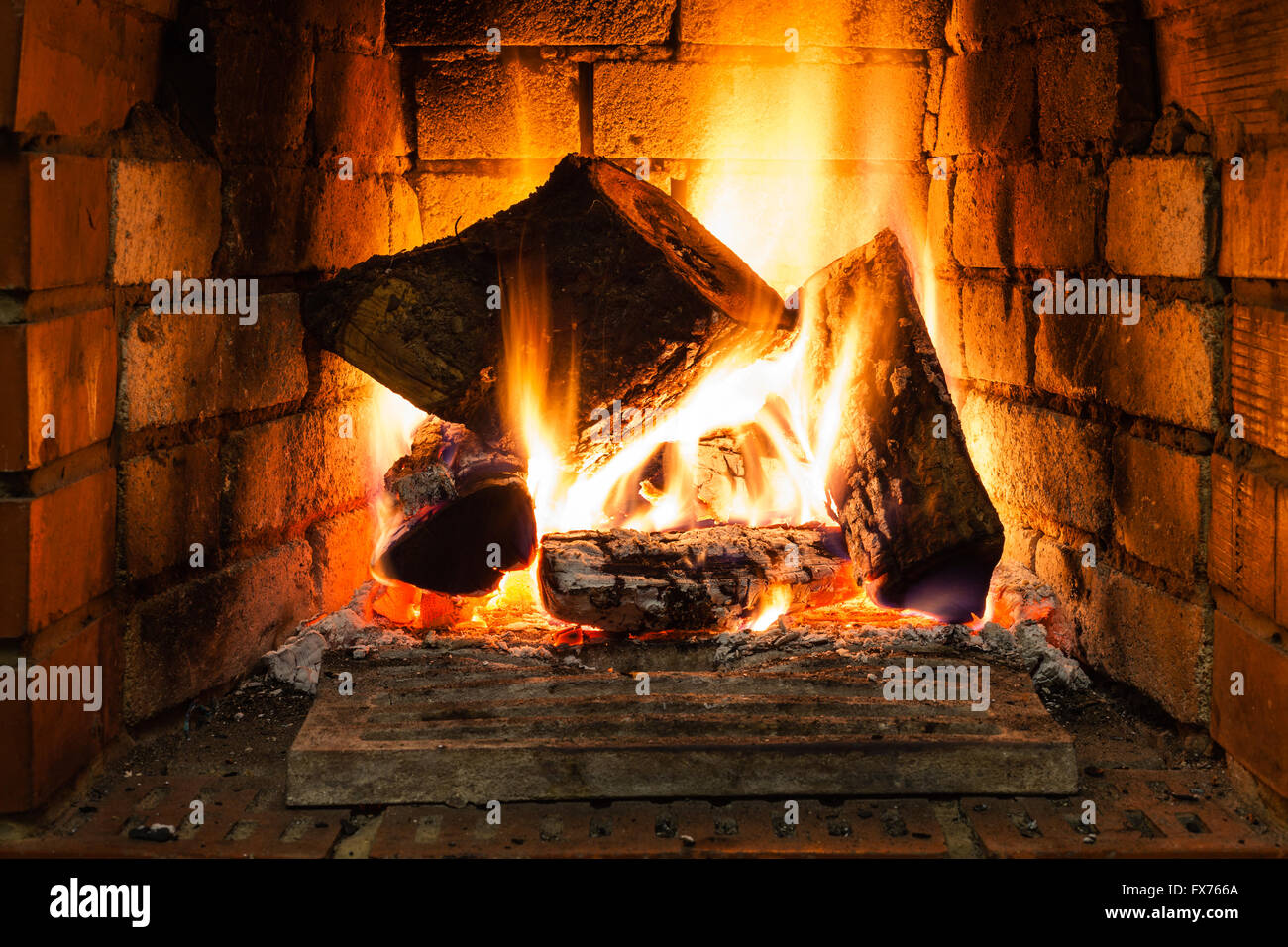 burning wood in fire-box of fireplace in country cottage Stock Photo