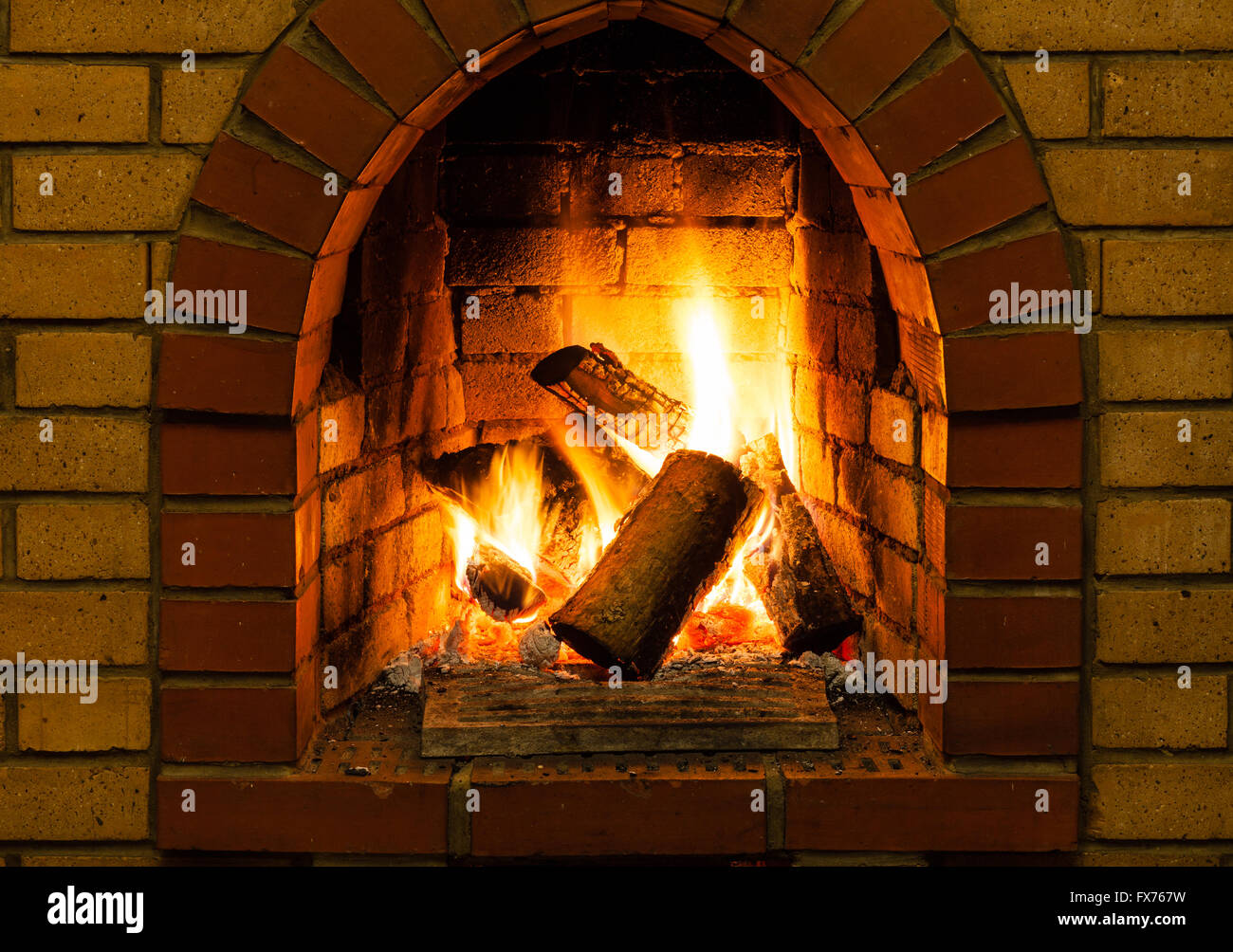 burning wooden logs in brick fireplace in country cottage Stock Photo