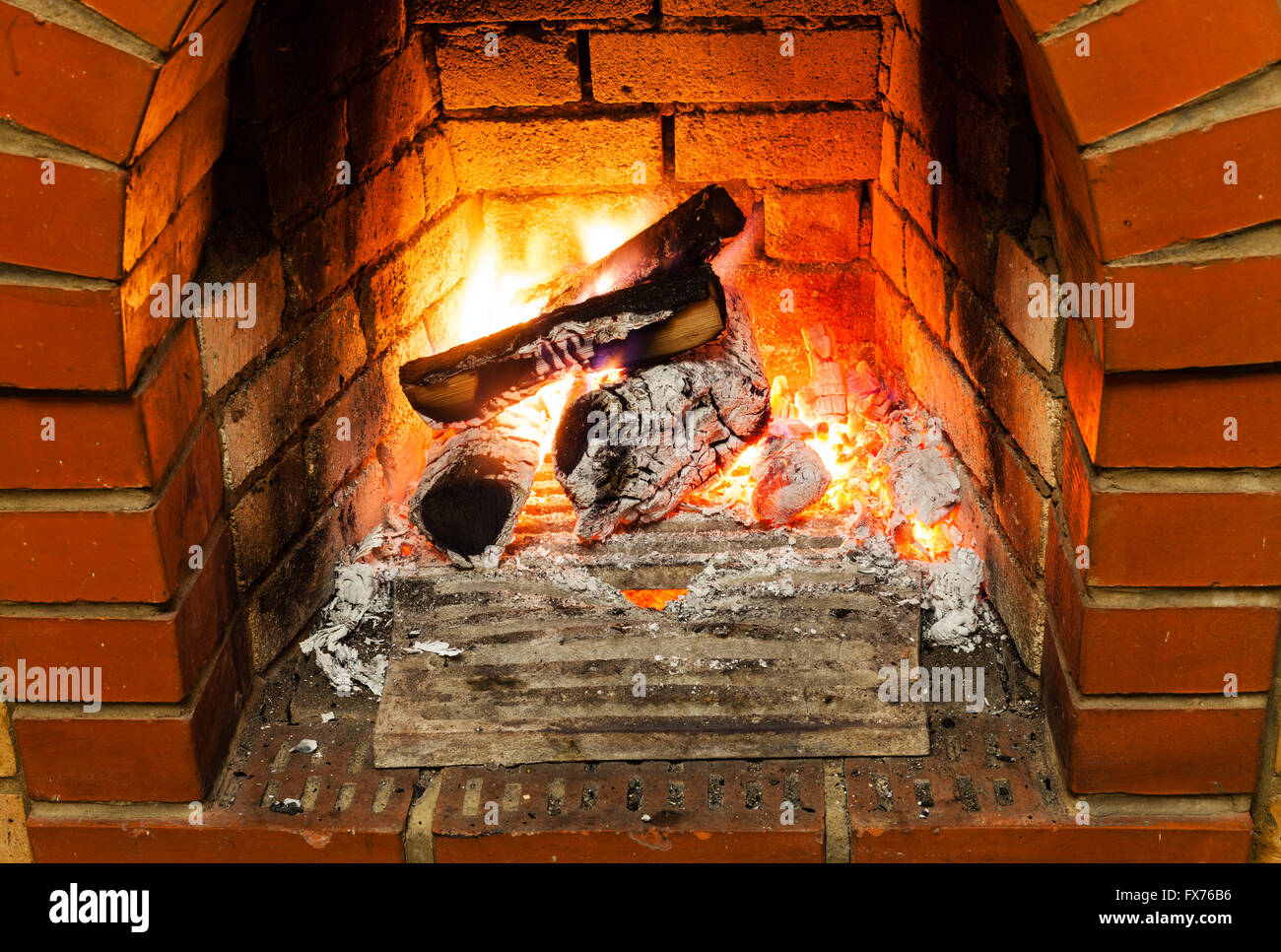 ash, coal and burning firewood in fireplace in country cottage Stock Photo