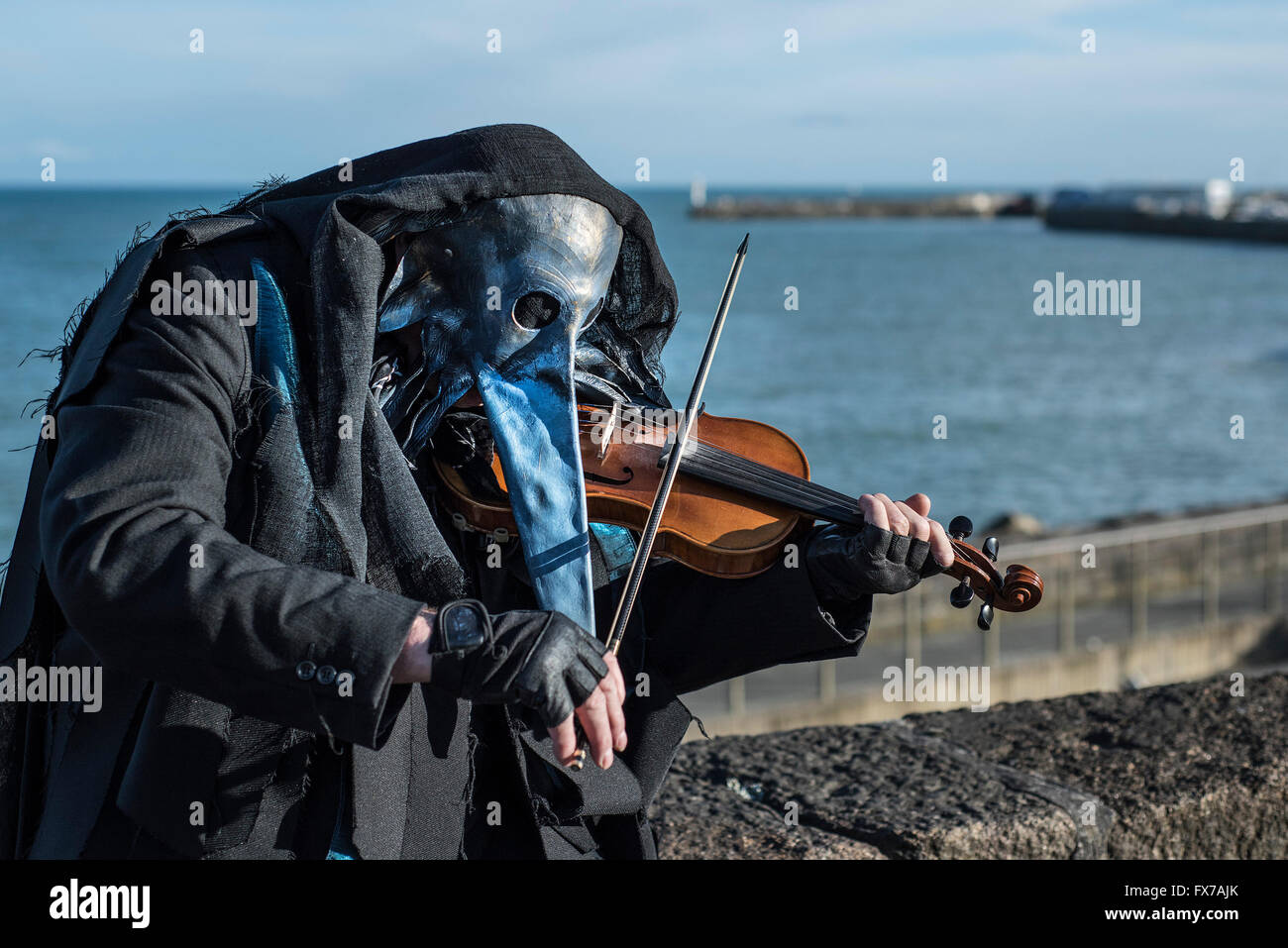 A masked guiser plays the violin. Stock Photo