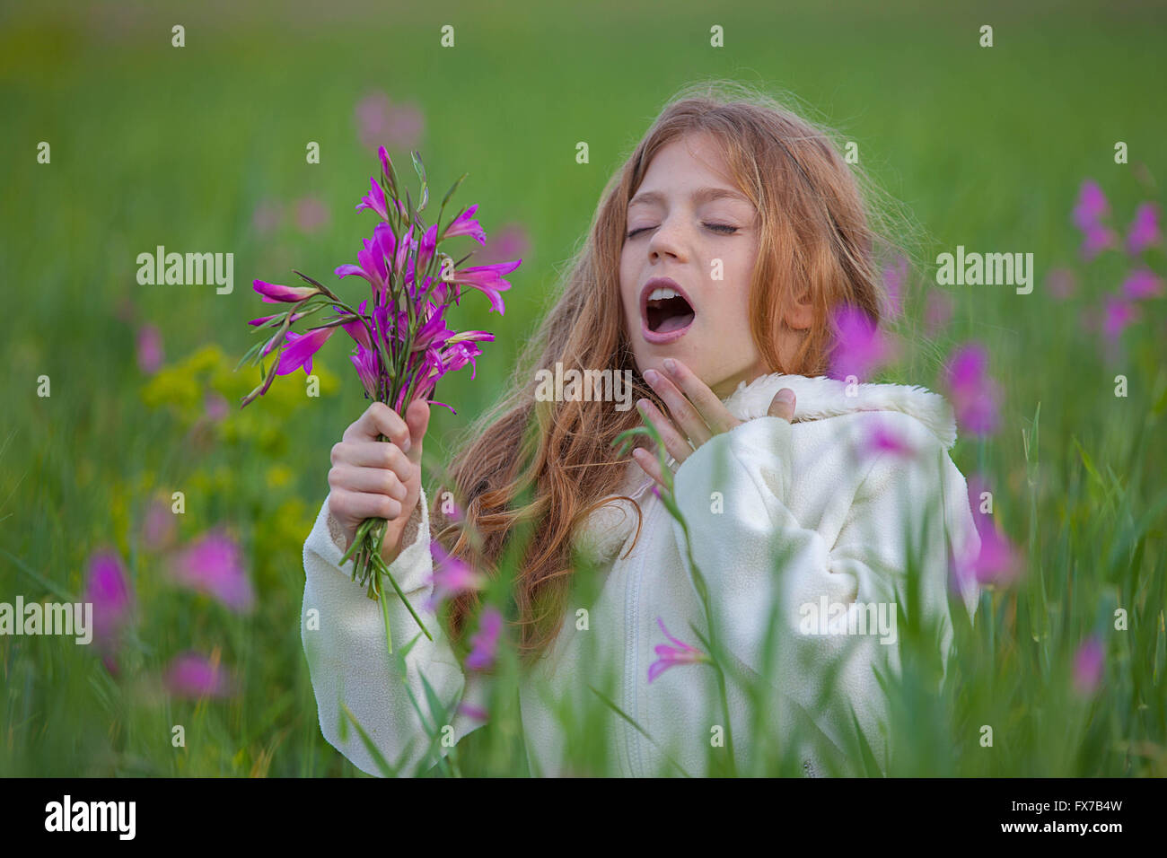 child sneezing allergic to flower pollen in summer Stock Photo