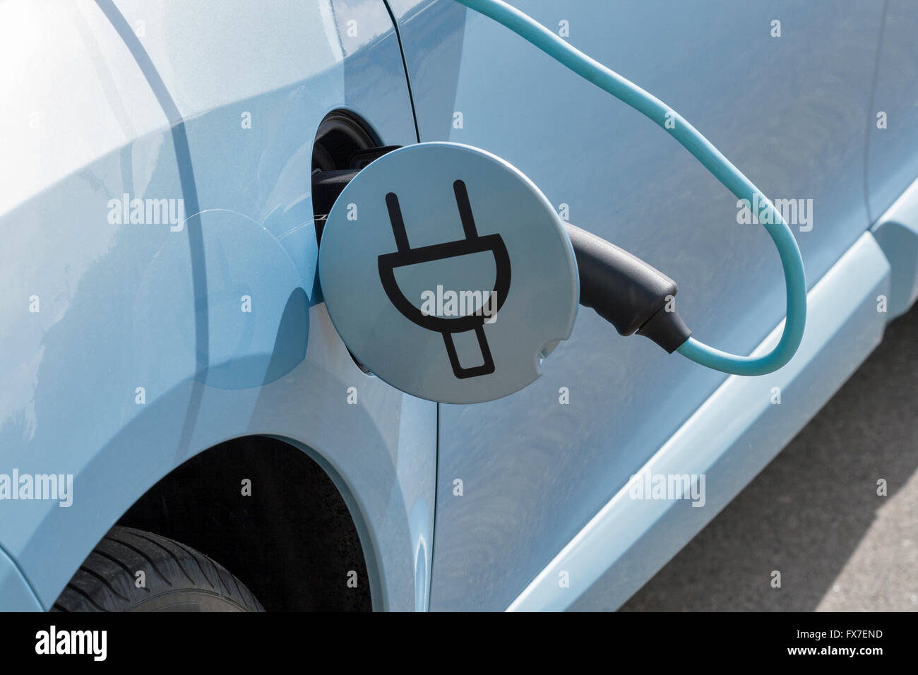 Charging an electric car with the power cable supply plugged in, closeup Stock Photo