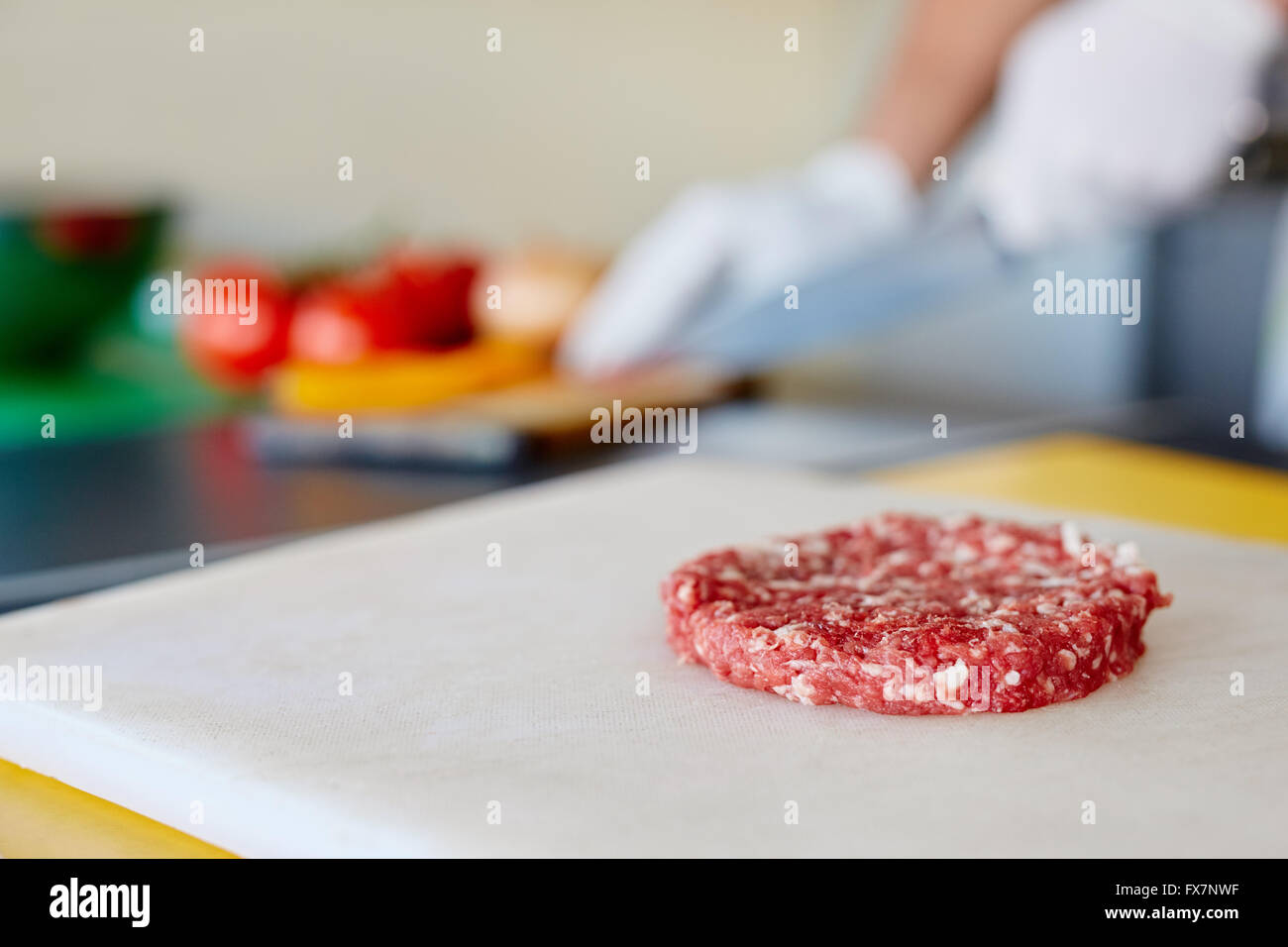 Raw hamburger patty on white board waiting to be seasoned Stock Photo