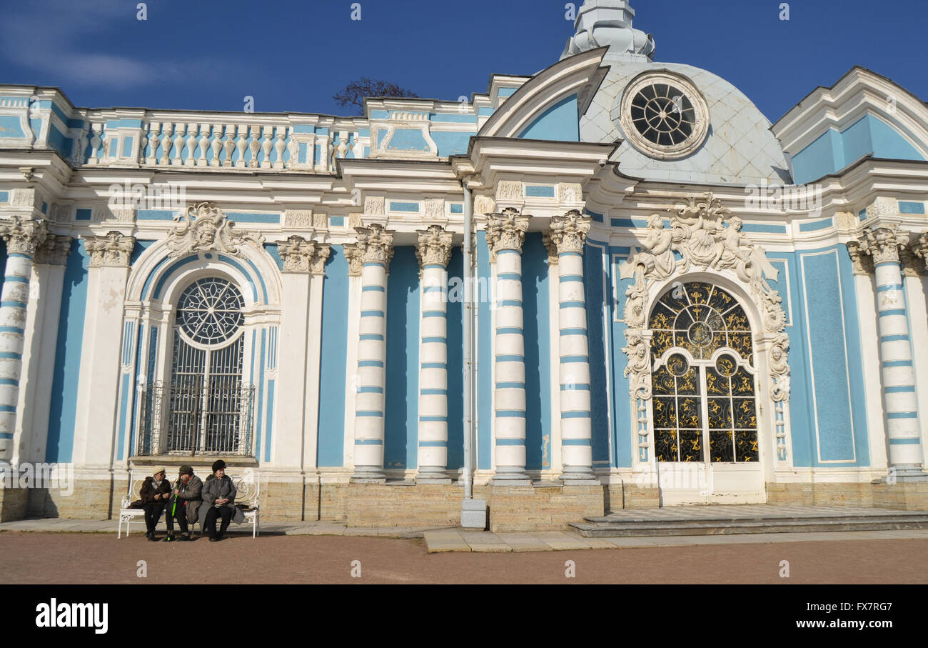 Old women sitting in the sun in front of blue mansion, Russia Stock Photo