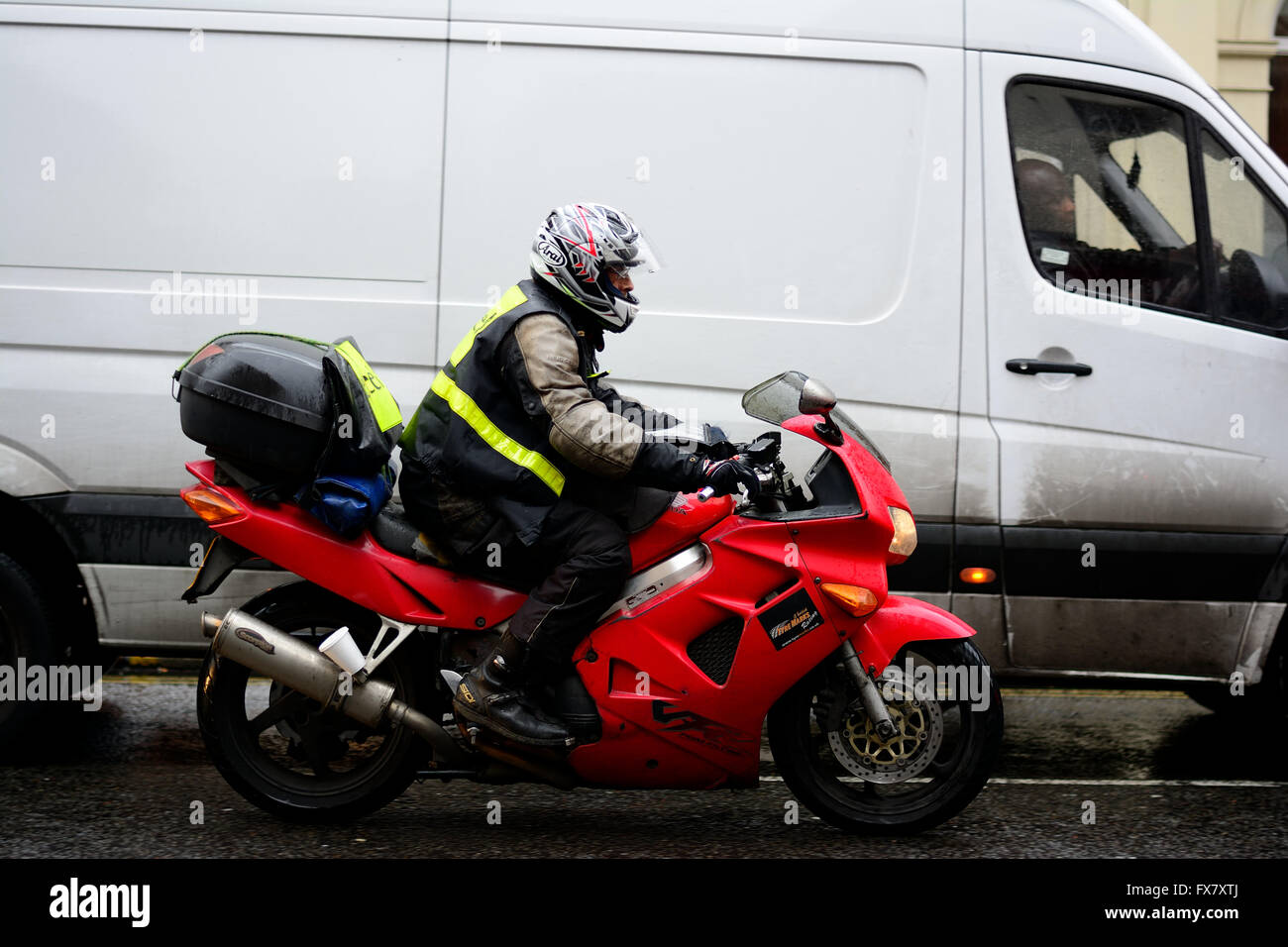 Red Motorcycle overtaking a white van during wet weather Stock Photo