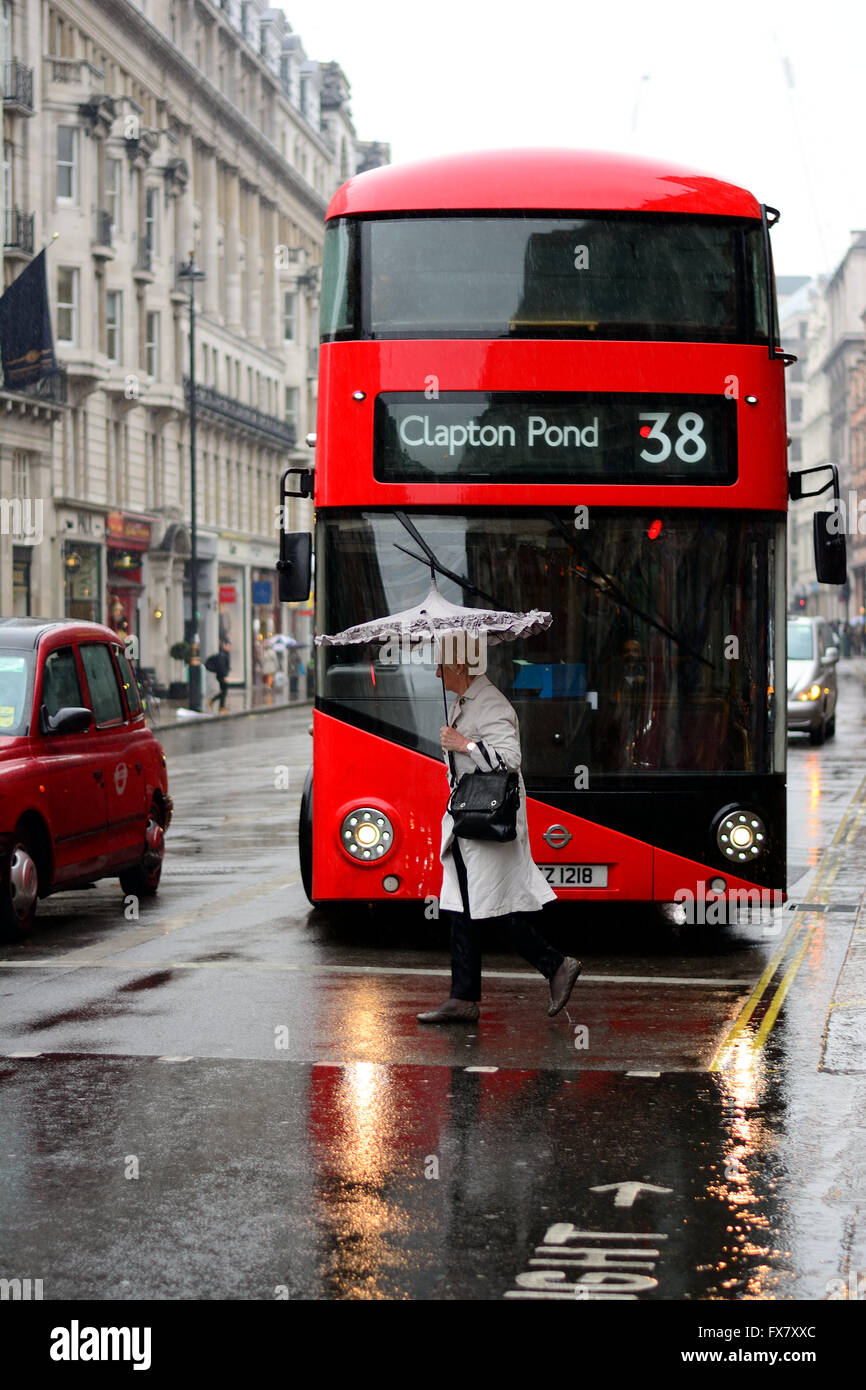 Woman with umbrella walking in front of Bus in London in wet weather Stock Photo Alamy