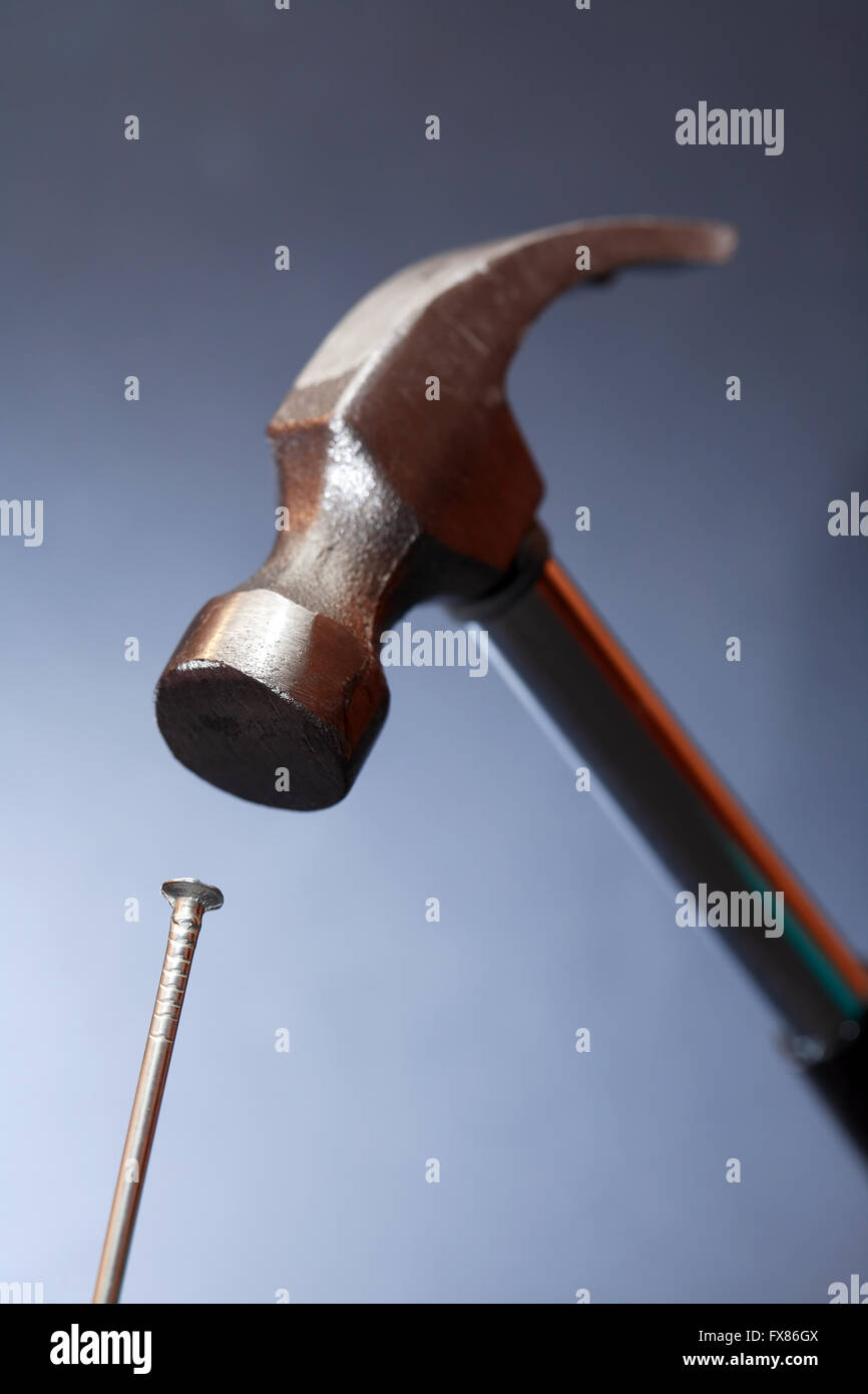 Work tool. Metal hammer above nail on nice dark background Stock Photo