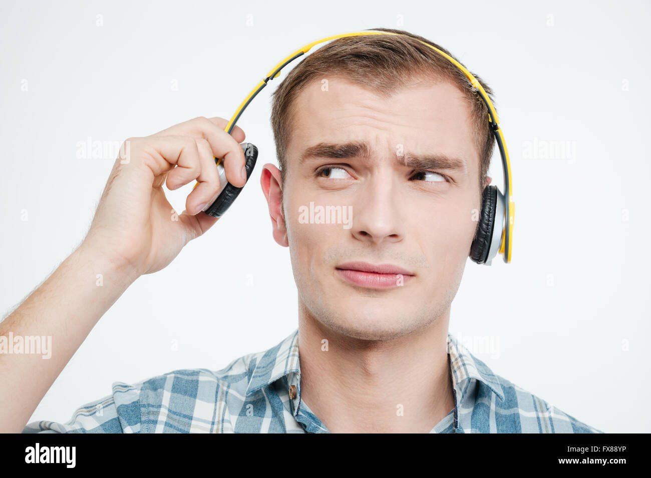 Unhappy handsome young man taking off headphones over white background Stock Photo