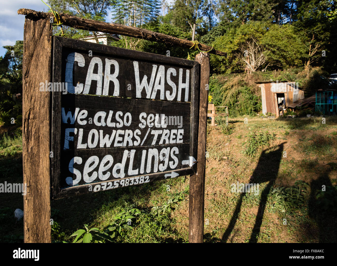 Diversification Kenyan style - sign outside a small car wash  business near Voi in southern Kenya also selling garden plants Stock Photo