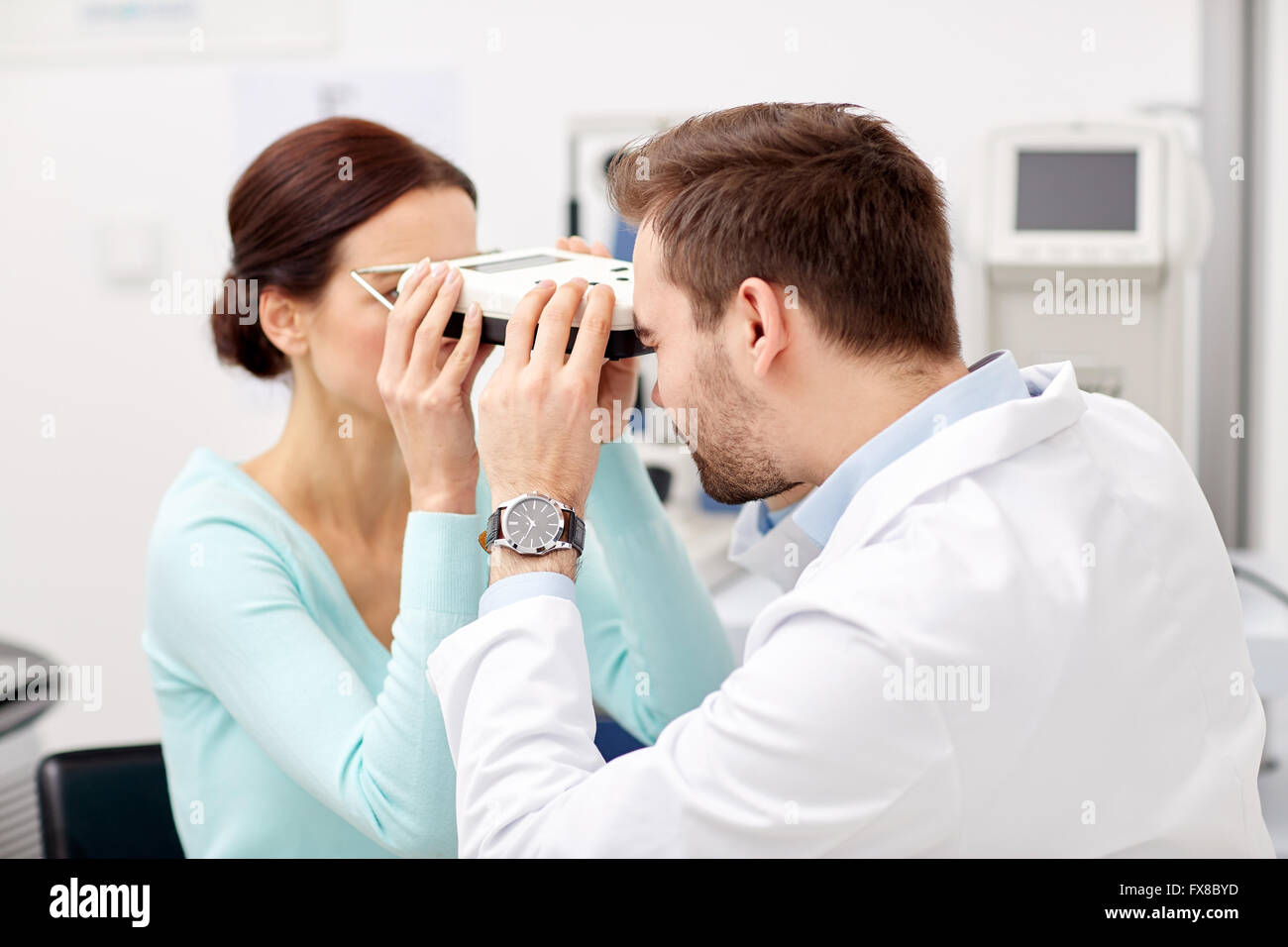 optician with pupilometer and patient at eye clinic Stock Photo