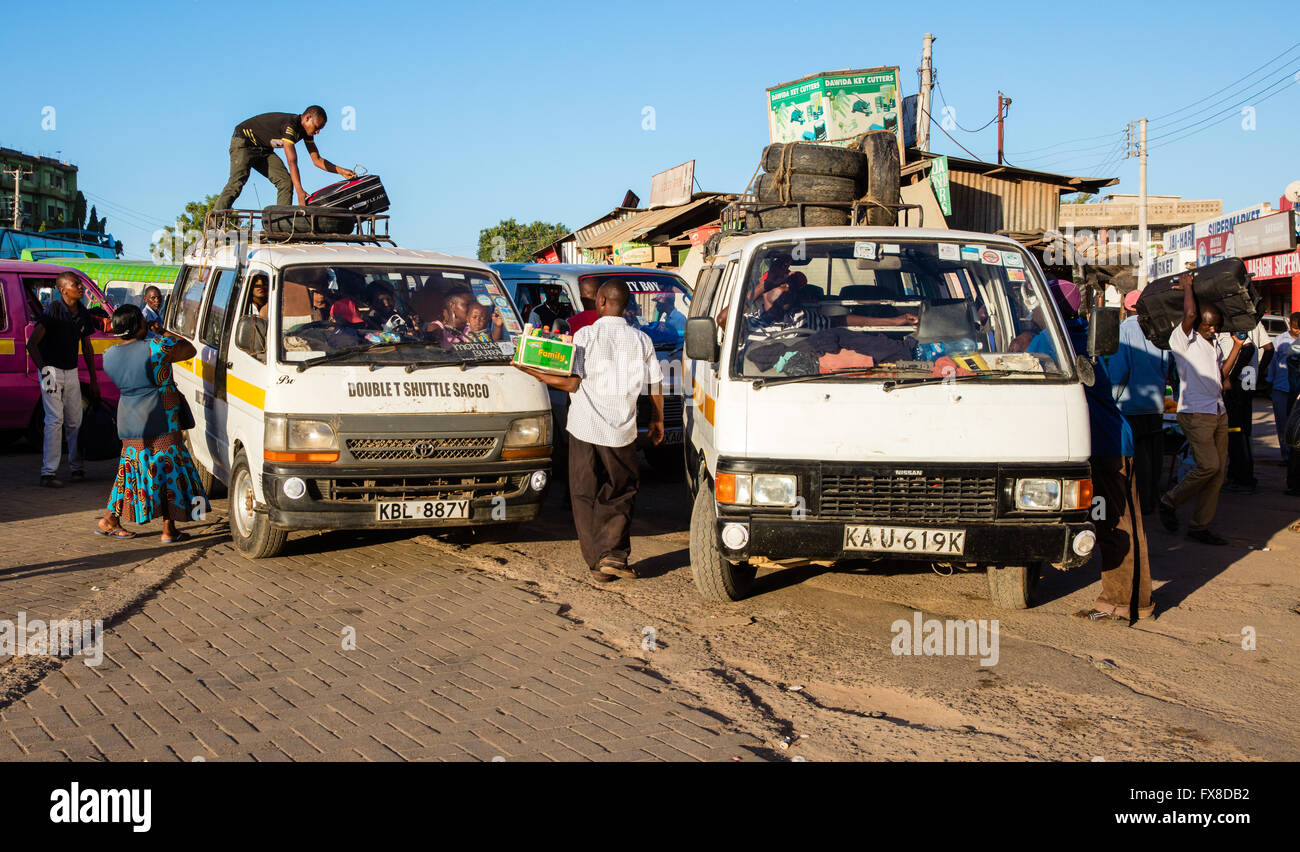 Bustling Voi bus station with people carriers or matatus being laden with goods and passengers - southern Kenya Stock Photo