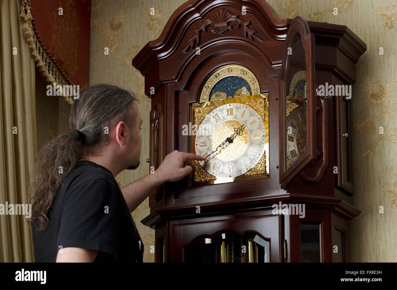 man adjusts analog old clocks in the room Stock Photo - Alamy