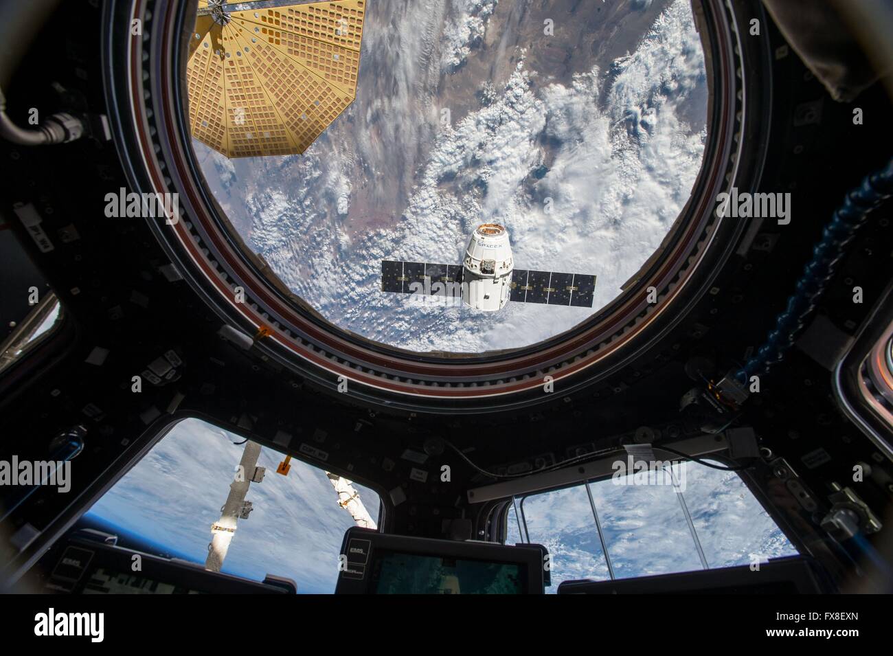 The SpaceX Dragon commercial cargo craft approaches the International Space Station for grapple and berthing seen from inside the Cupola module April 10, 2016 in Earth Orbit. The spacecraft is delivering 7,000 pounds of supplies, including the Bigelow Expandable Activity Module, known as BEAM. Stock Photo