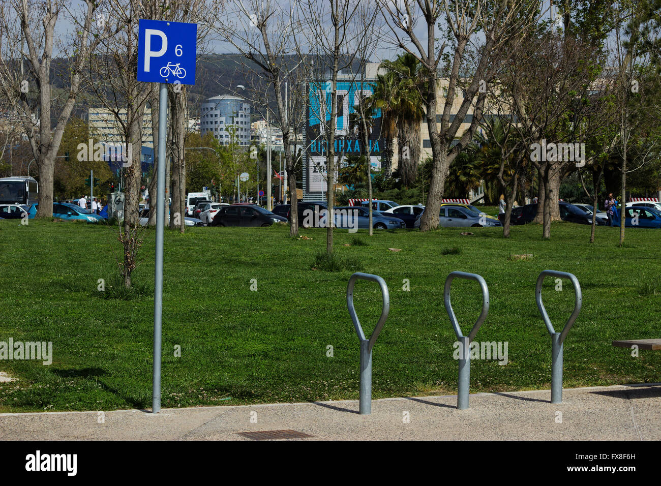 Empty bicycle parking space with sign next to a park at the New