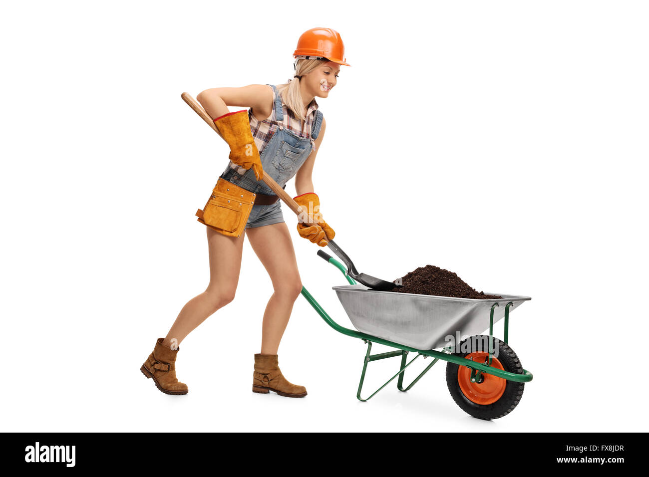 Female construction worker unloading a wheelbarrow full of dirt with a