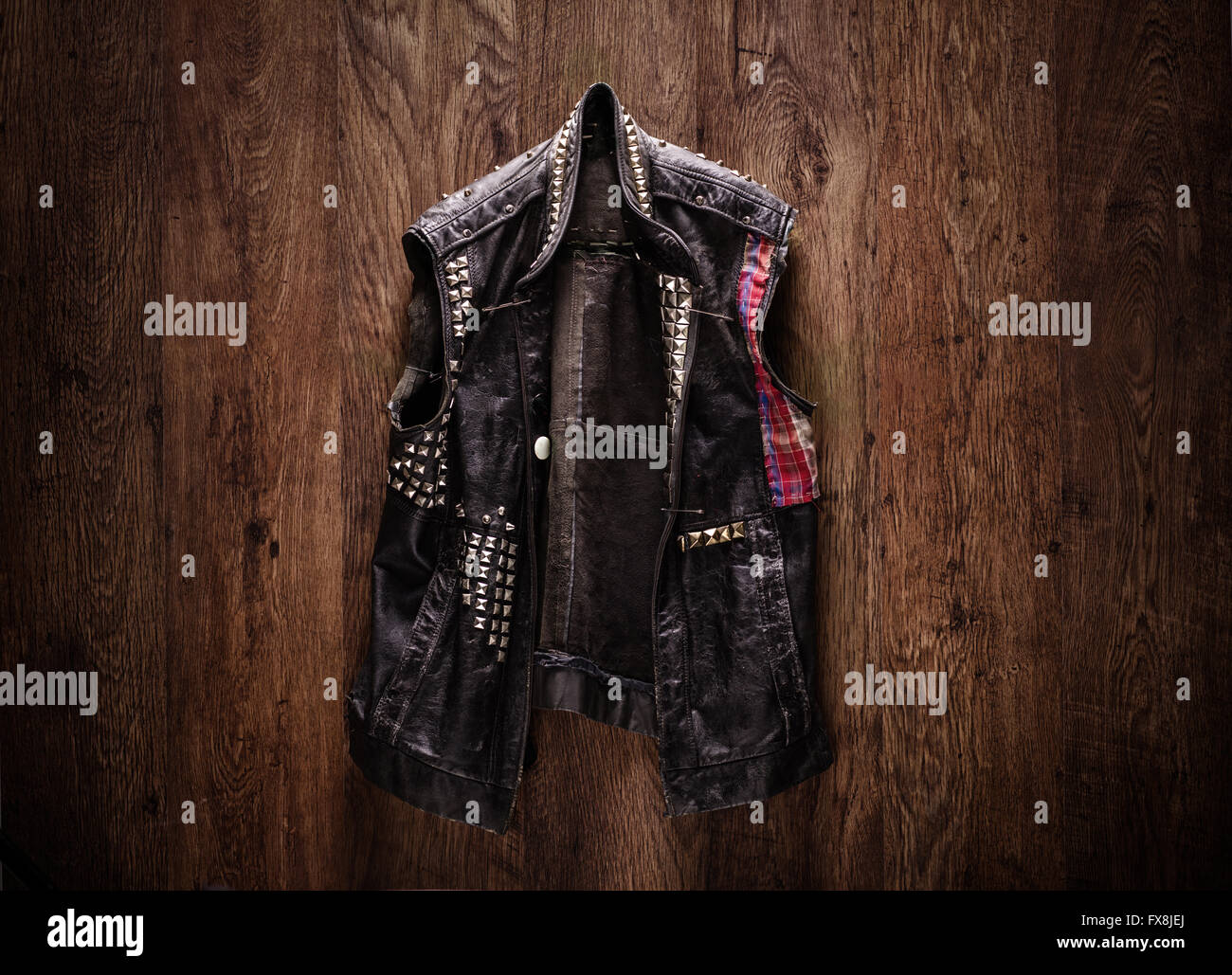 Old-school punk-rock leather jacket hanging on a wooden background Stock Photo