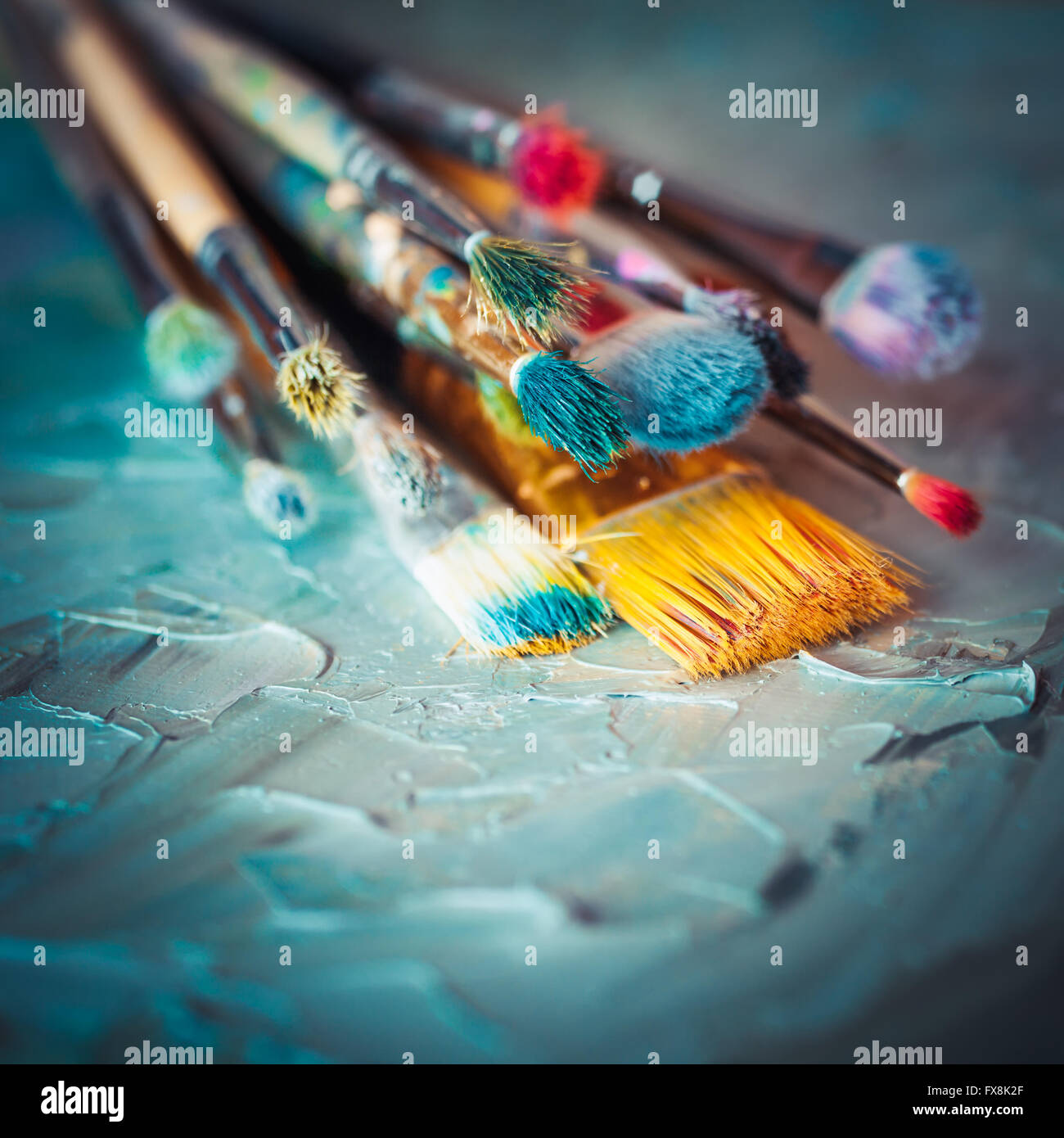 Paintbrushes on artist canvas covered with oil paints. Retro styled. Stock Photo
