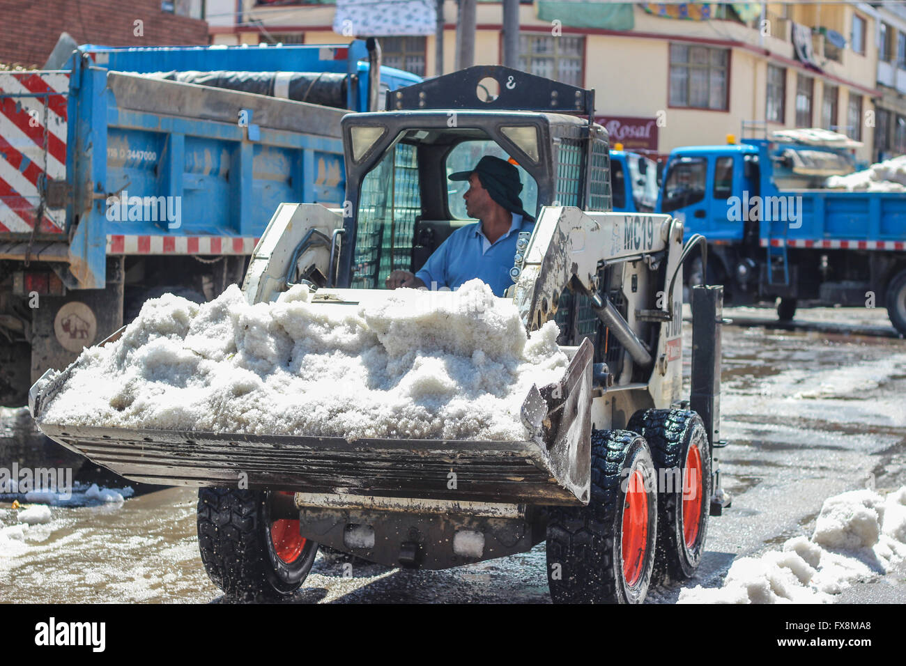 A person in a backhoe picks the hail after storm Stock Photo