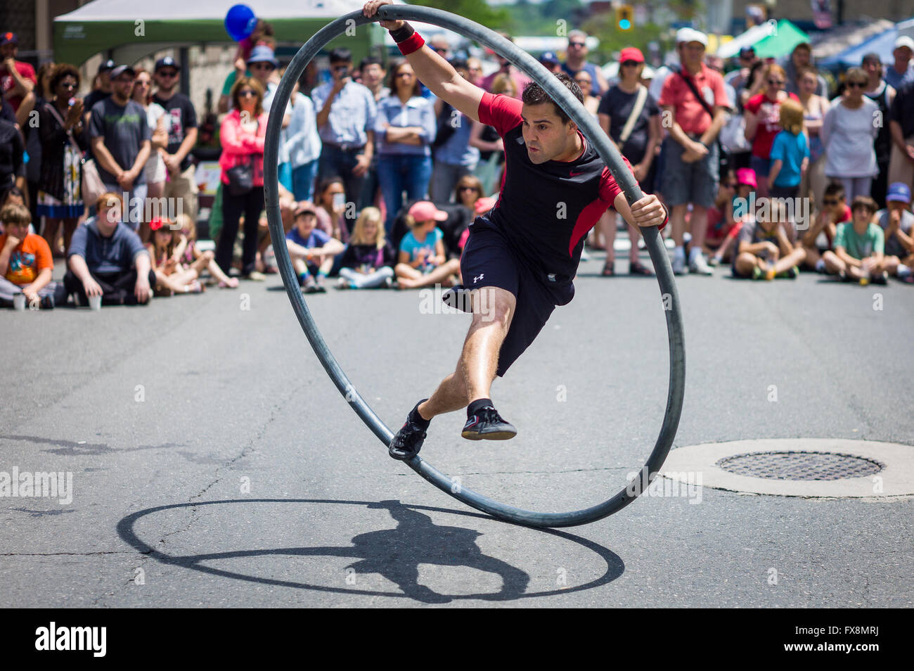 Acrobat performing in a street circus spinning inside a giant hoop during a summer festival. Stock Photo