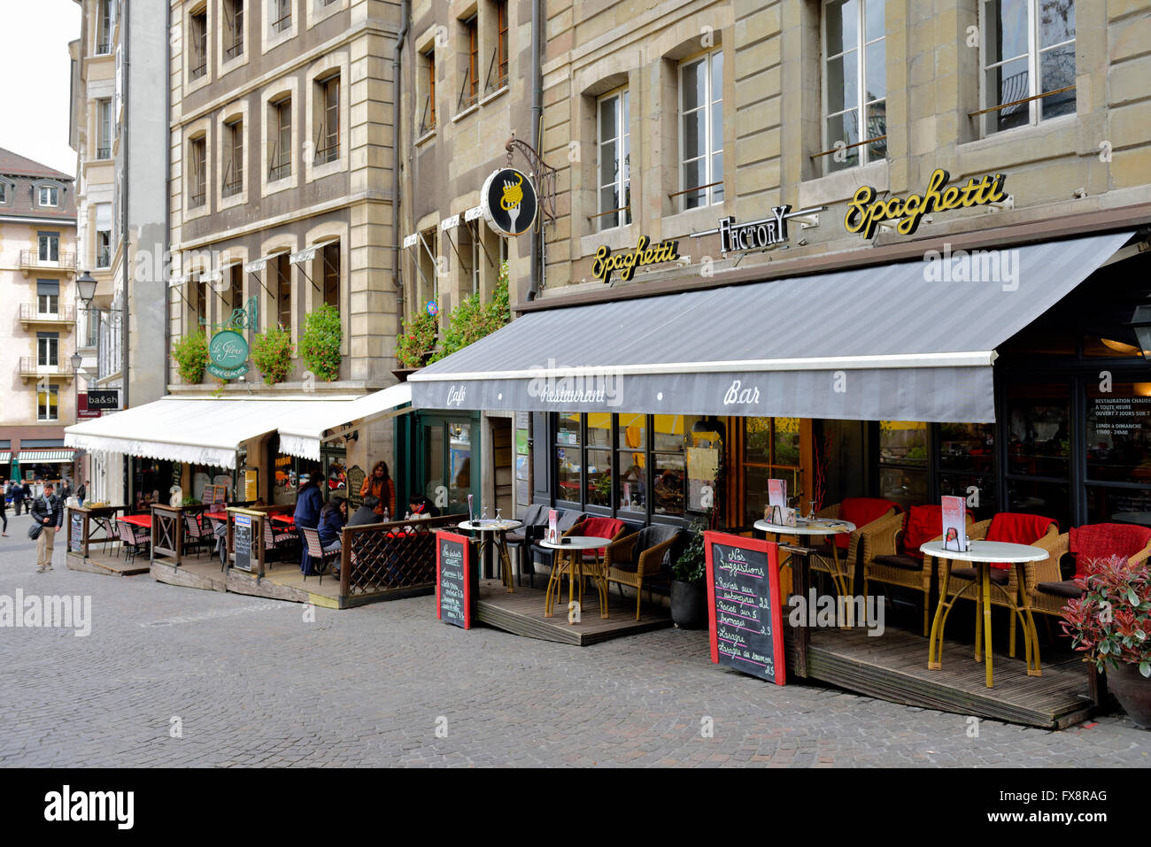 Restaurants with table and chairs eating outside by street, Geneva, Switzerland Stock Photo