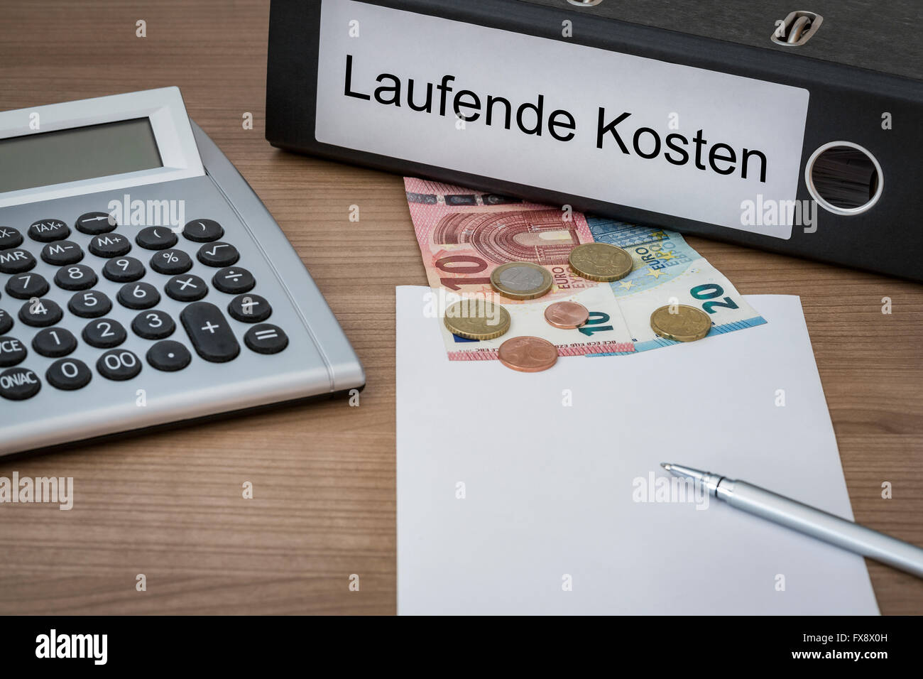Laufende Kosten (German Running costs) written on a binder on a desk with euro money calculator blank sheet and pen Stock Photo