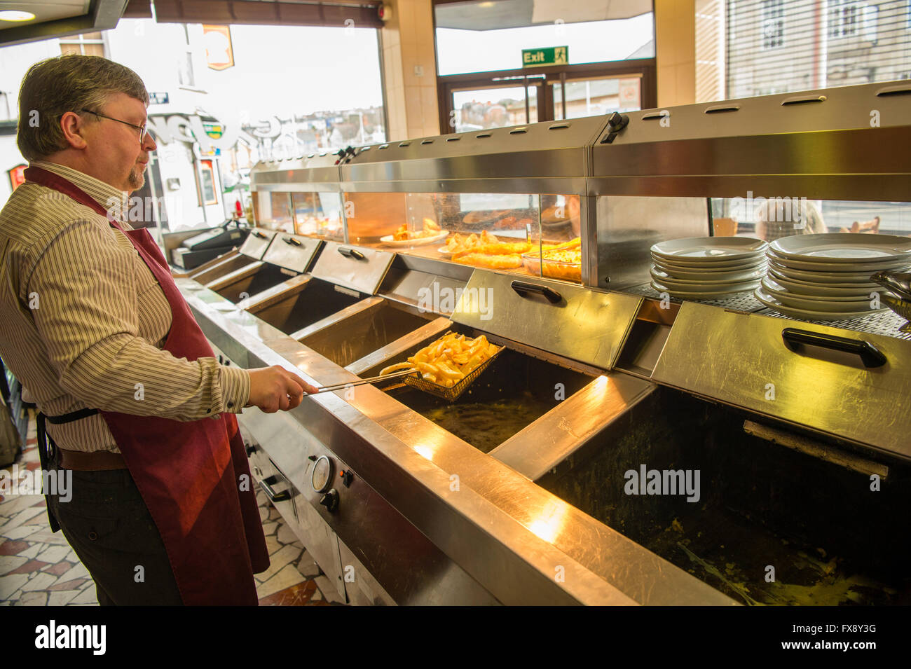 A man working preparing freshly fried food in the Express Cafe , a