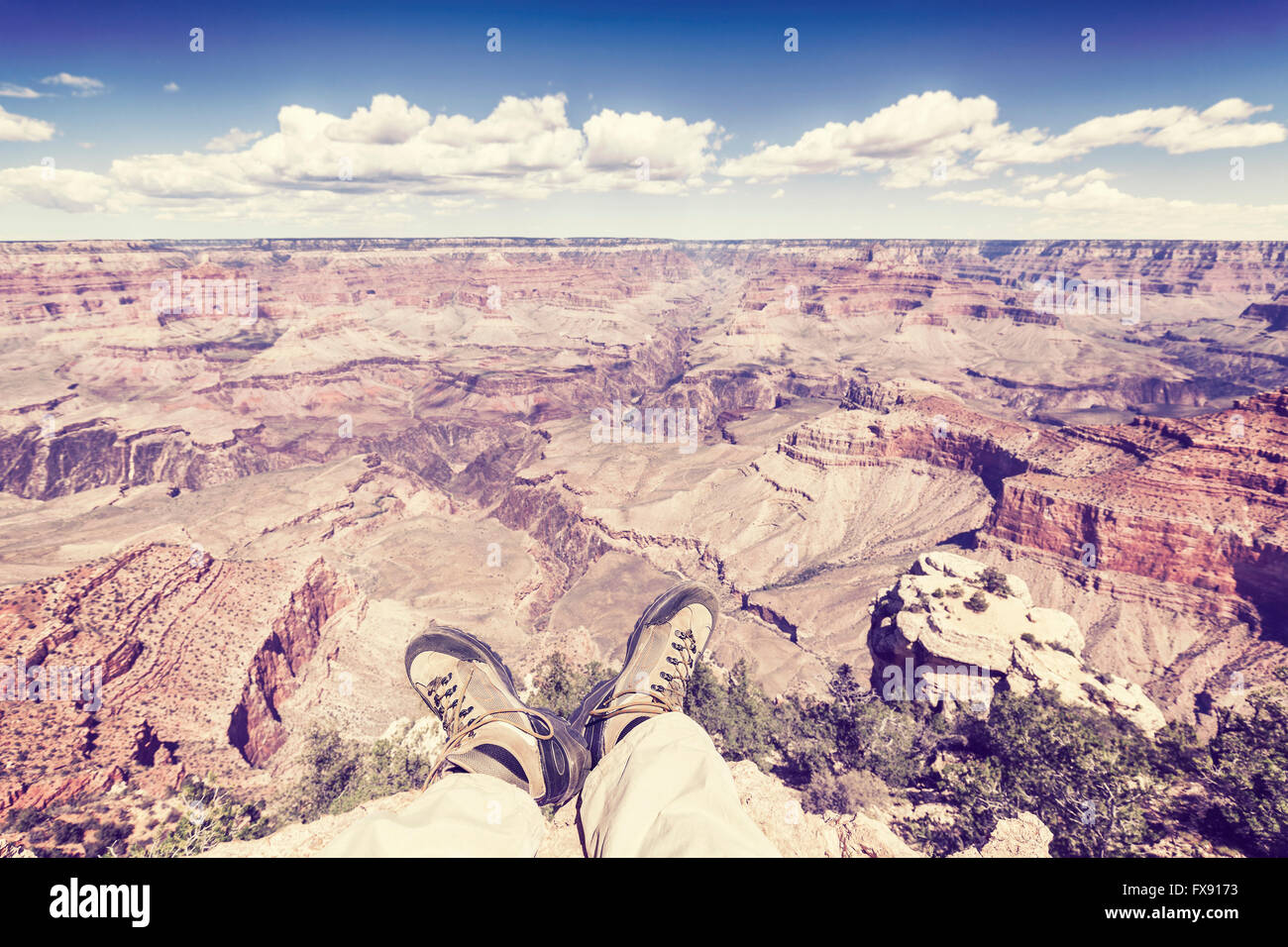 Vintage toned legs with old trekking shoes by the Grand Canyon cliff