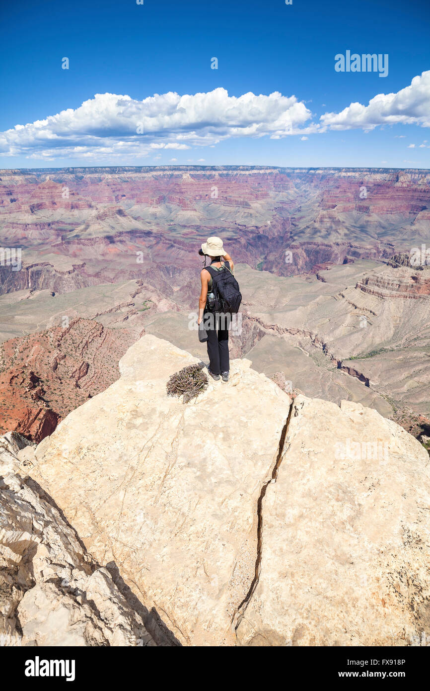 Young woman standing on the edge of a cliff and taking pictures of the Grand Canyon, hobby and adventure concept. Stock Photo
