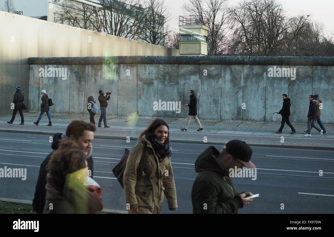 People walk next to a remaining part of the wall at the Berlin Wall Memorial in Berlin at Bernauer Straße on December, 30, 2015. The photo was taken trough a window. Photo: Wolfram Steinberg/dpa Stock Photo
