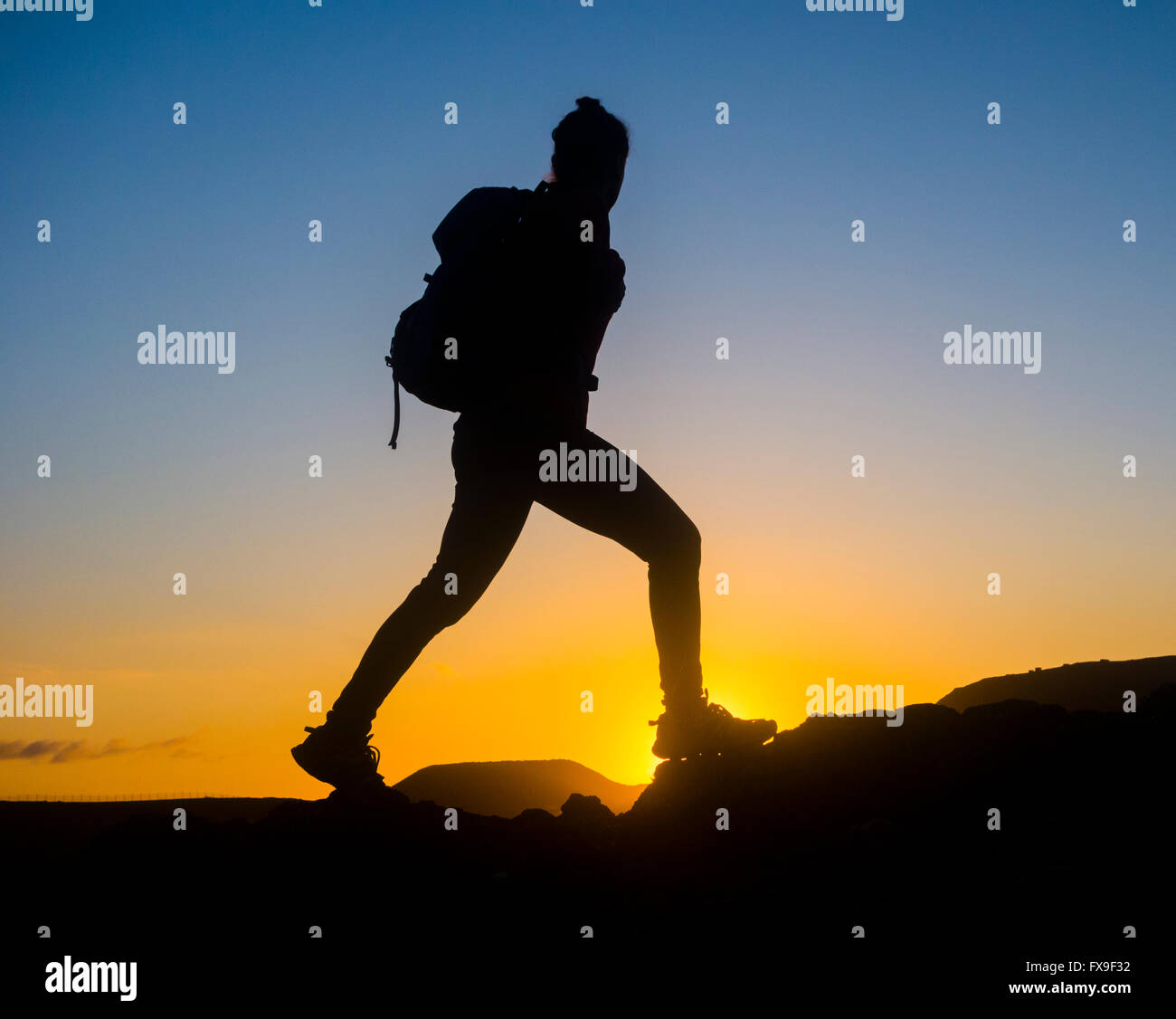 Las Palmas, Gran Canaria, Canary Islands, Spain, 13th April 2016. Weather: A female mountain runner on summit of mountain overlooking Las Palmas city at sunrise on a glorious Wednesday morning on Gran Canaria. Credit:  Alan Dawson News/Alamy Live News Stock Photo