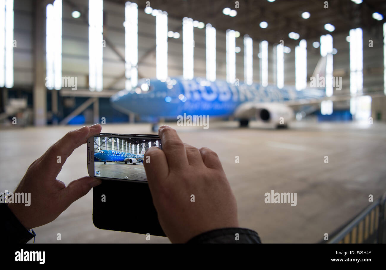 Hanover, Germany. 13th Apr, 2016. An invited guest takes a picture of an aircraft of the type Boeing 737-800 of carrier TUI, with the writing 'Robinson' on it, stands during a ceremonial aircraft launching in the hangar at the airport in Hanover, Germany, 13 April 2016. Travel agent and airline TUI as launched two aircraft named as 'Tui Magic Life' and 'Robinson'. TUI has launched a marketing initiative to present its fleet of aircraft as branding ambassadors, advertising TUIs own brand of hotels. PHOTO: SEBASTIAN GOLLNOW/dpa/Alamy Live News Stock Photo