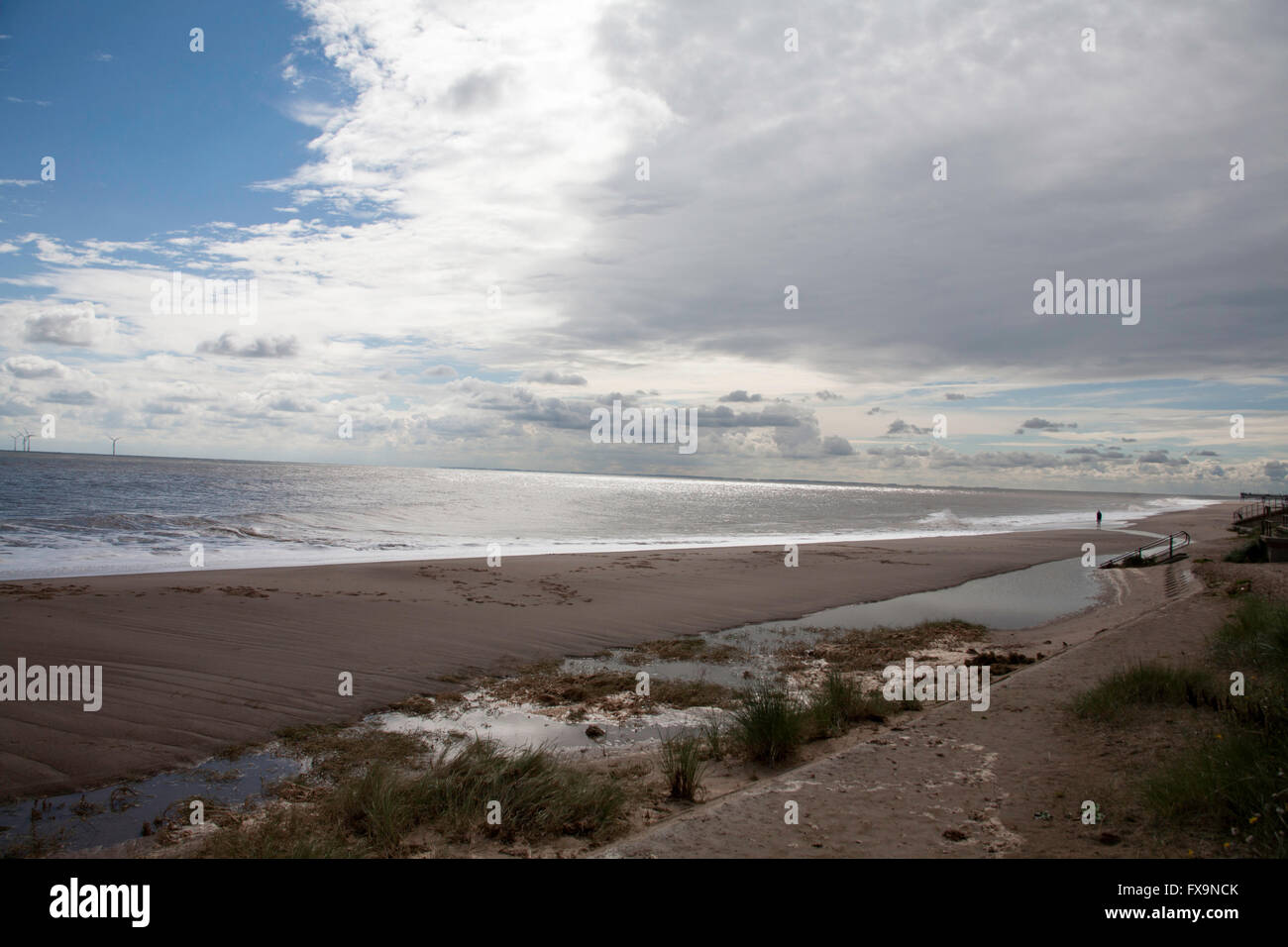 Storm clouds clearing the beach with wind farm in the background ...